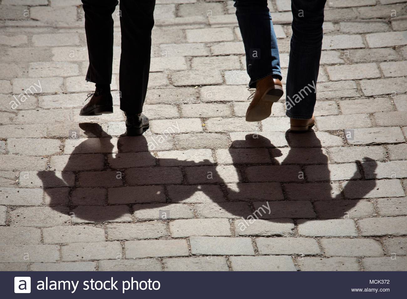 Schatten von zwei Menschen gingen Hand in Hand an einem schönen Tag, eine alte Straße in Salzburg, Österreich. Credit: reallifephotos/Alamy Stockfoto