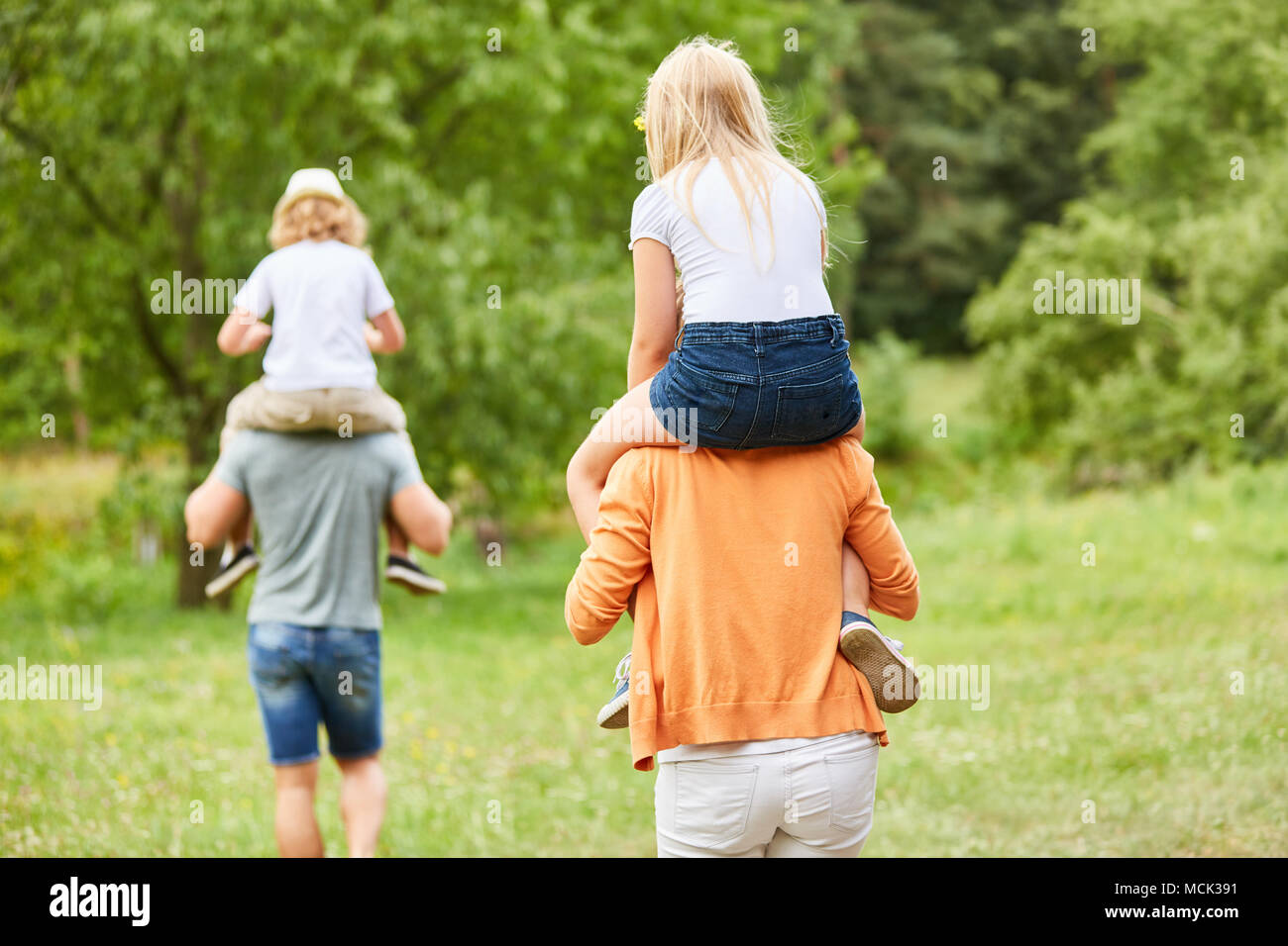 Familienurlaub mit Kindern Huckepack auf dem Rücken der Eltern. Stockfoto