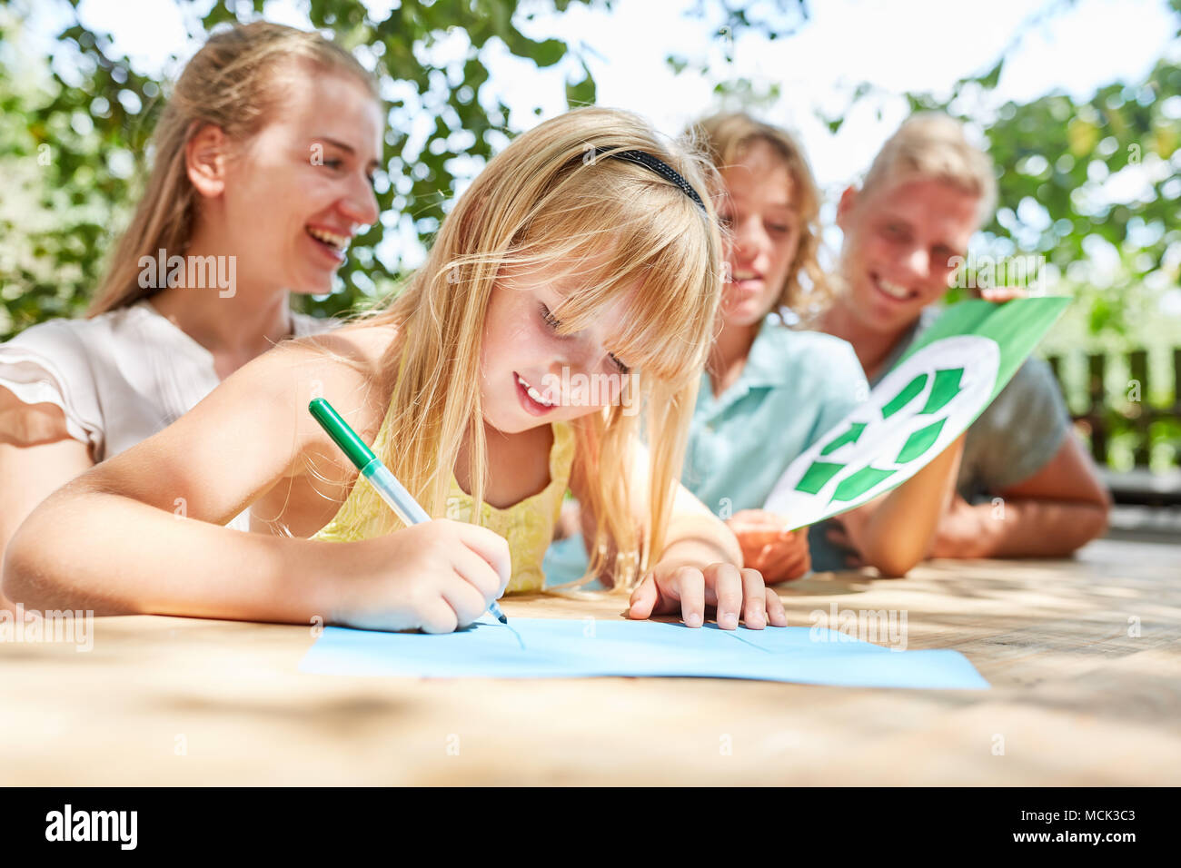 Familie und Mädchen beim Zeichnen und Bruder holding Logo recyceln Stockfoto