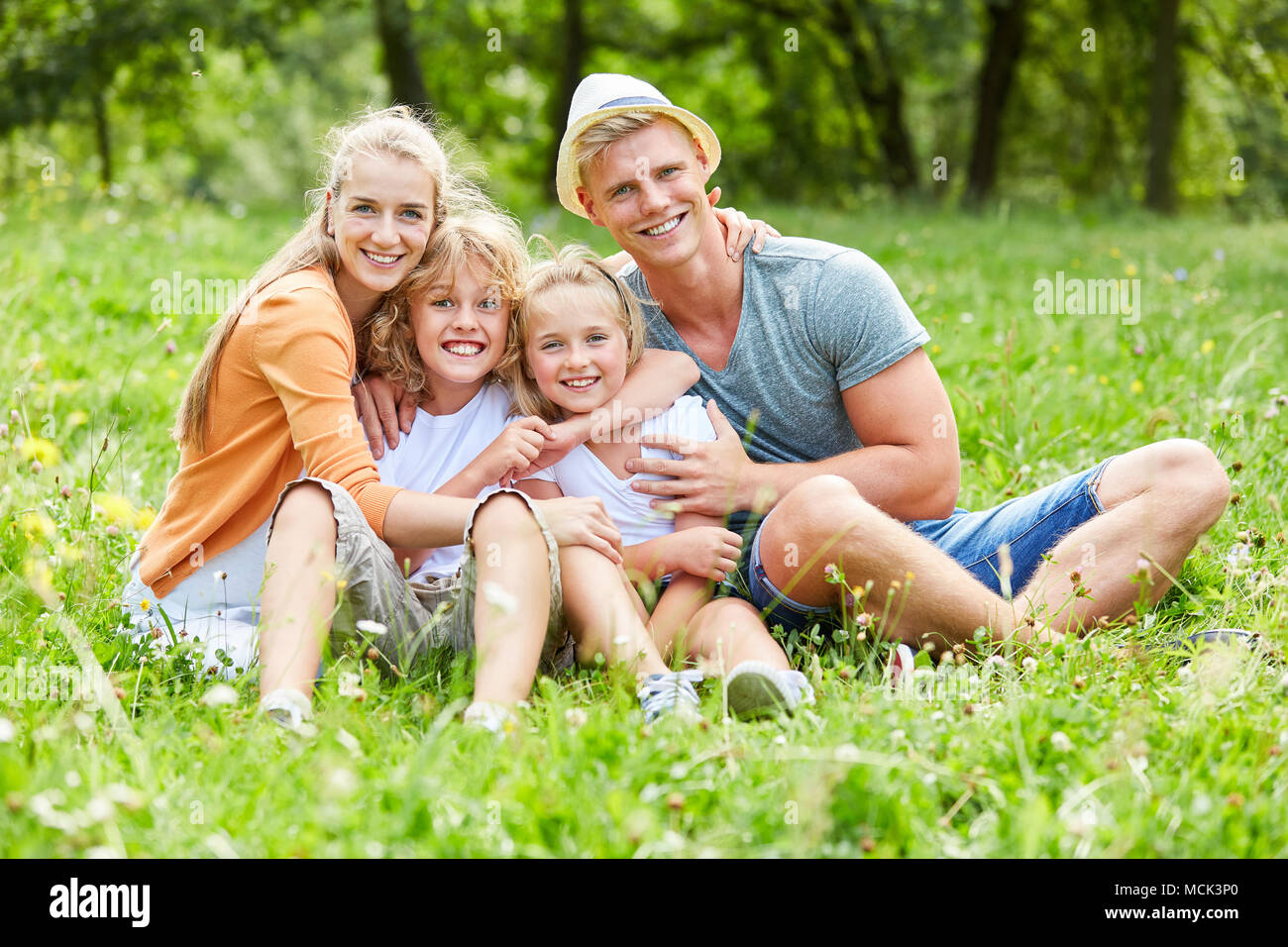 Glückliche Eltern und ihre zwei Kinder sind zusammen sitzen im Garten Stockfoto
