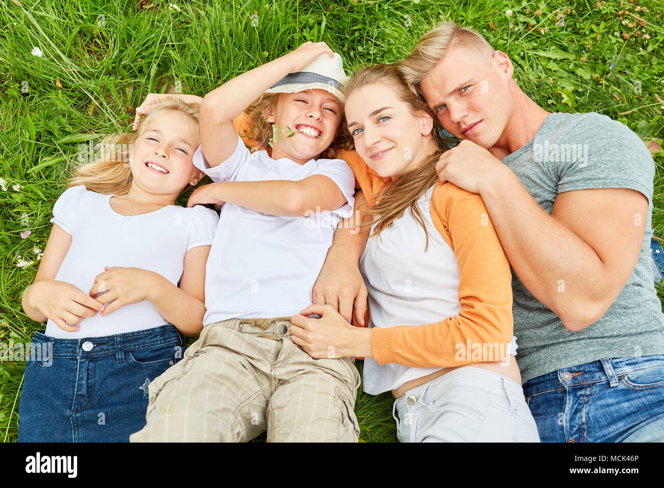 Eltern und zwei Kinder sind zusammen im Gras im Garten Stockfoto
