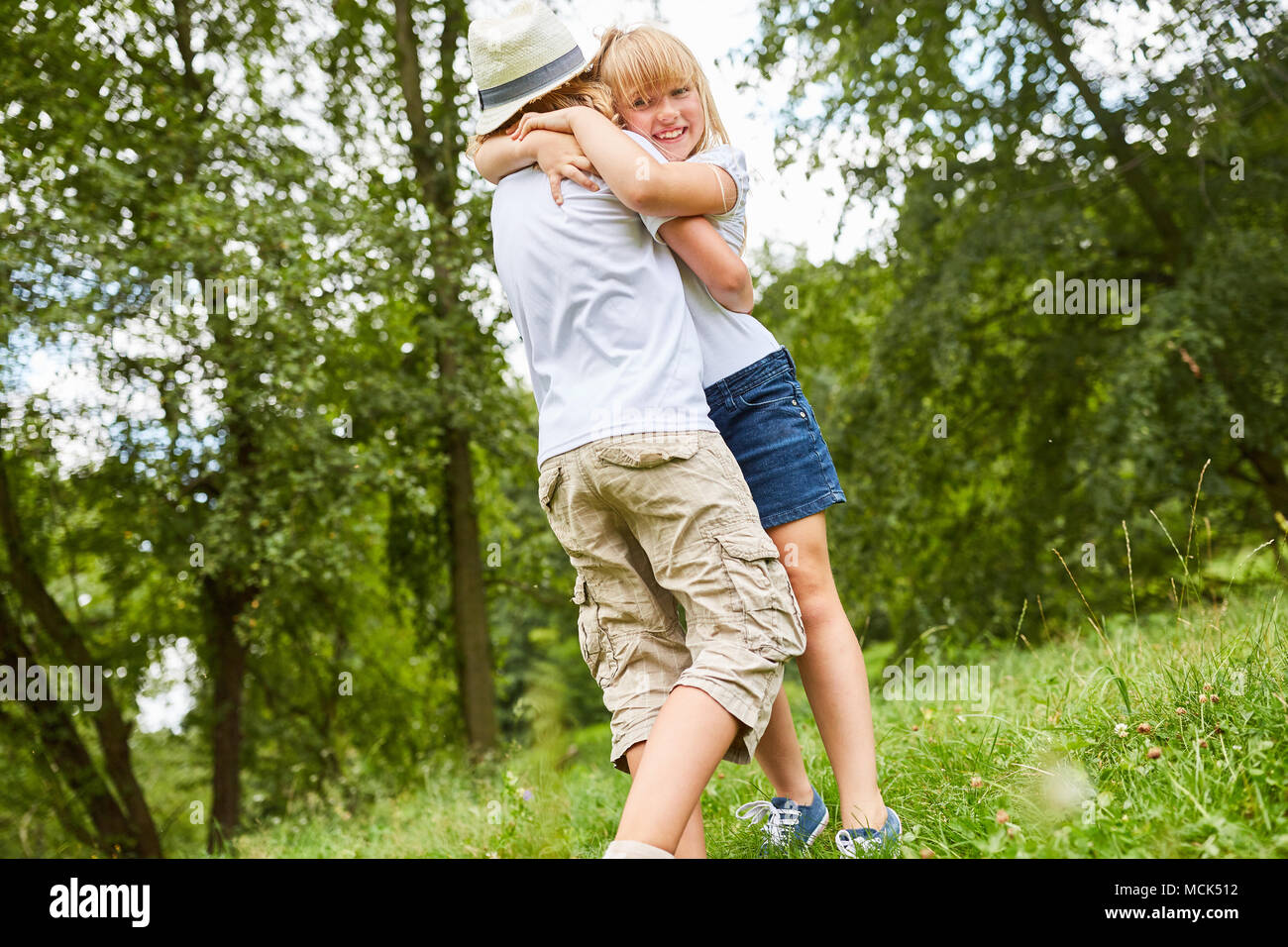 Geschwister Kinder begrüßen sich mit einer Umarmung auf einer Wiese Stockfoto
