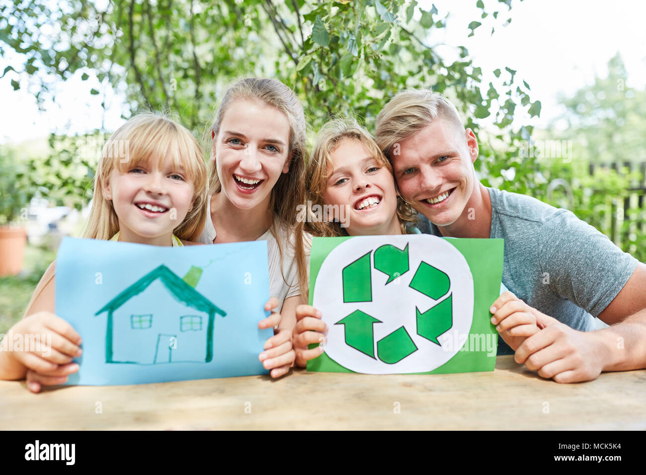 Glückliche Familie mit Haus und Recycling Logo Stockfoto