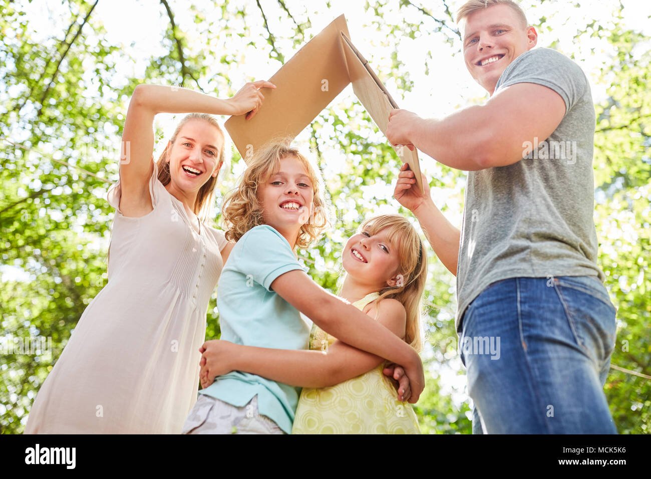 Glückliche Kinder stehen unter einem Dach als Symbol einer Home Stockfoto