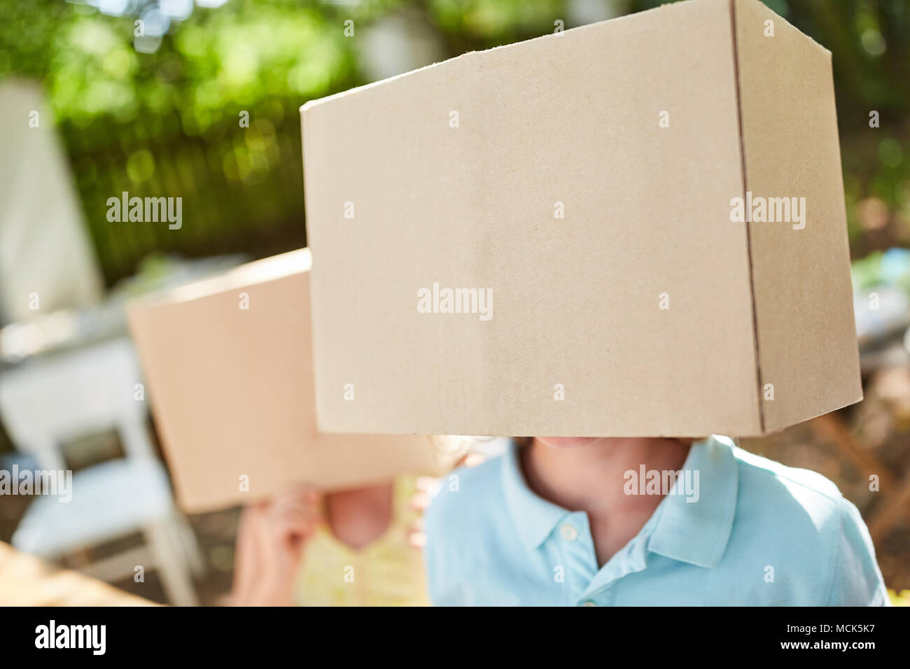 Zwei Kinder ihre Gesichter unter Kartons ausblenden Stockfoto