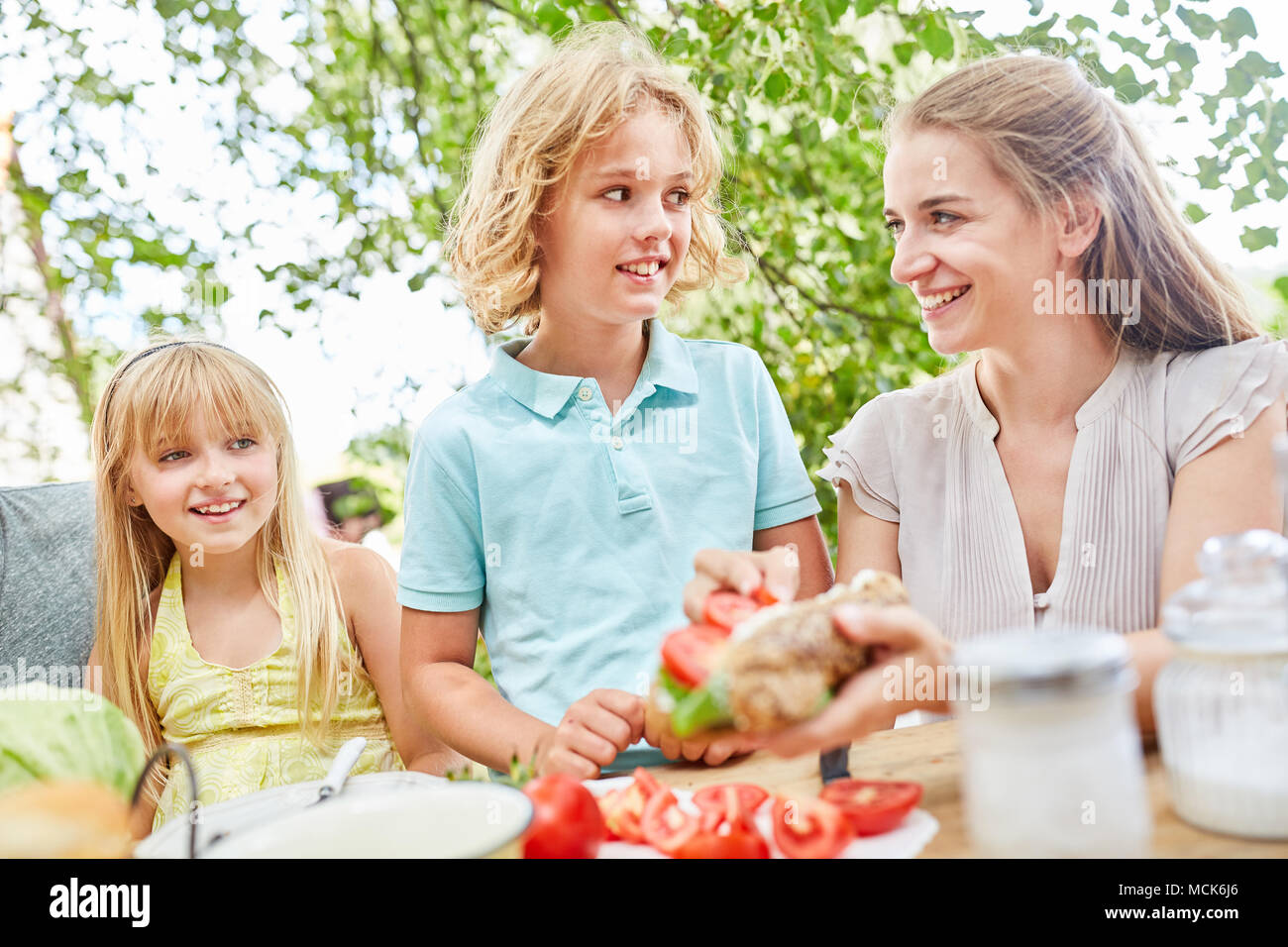 Mutter und Sohn freuen sich auf das Frühstück mit Baguette und Tomaten Stockfoto