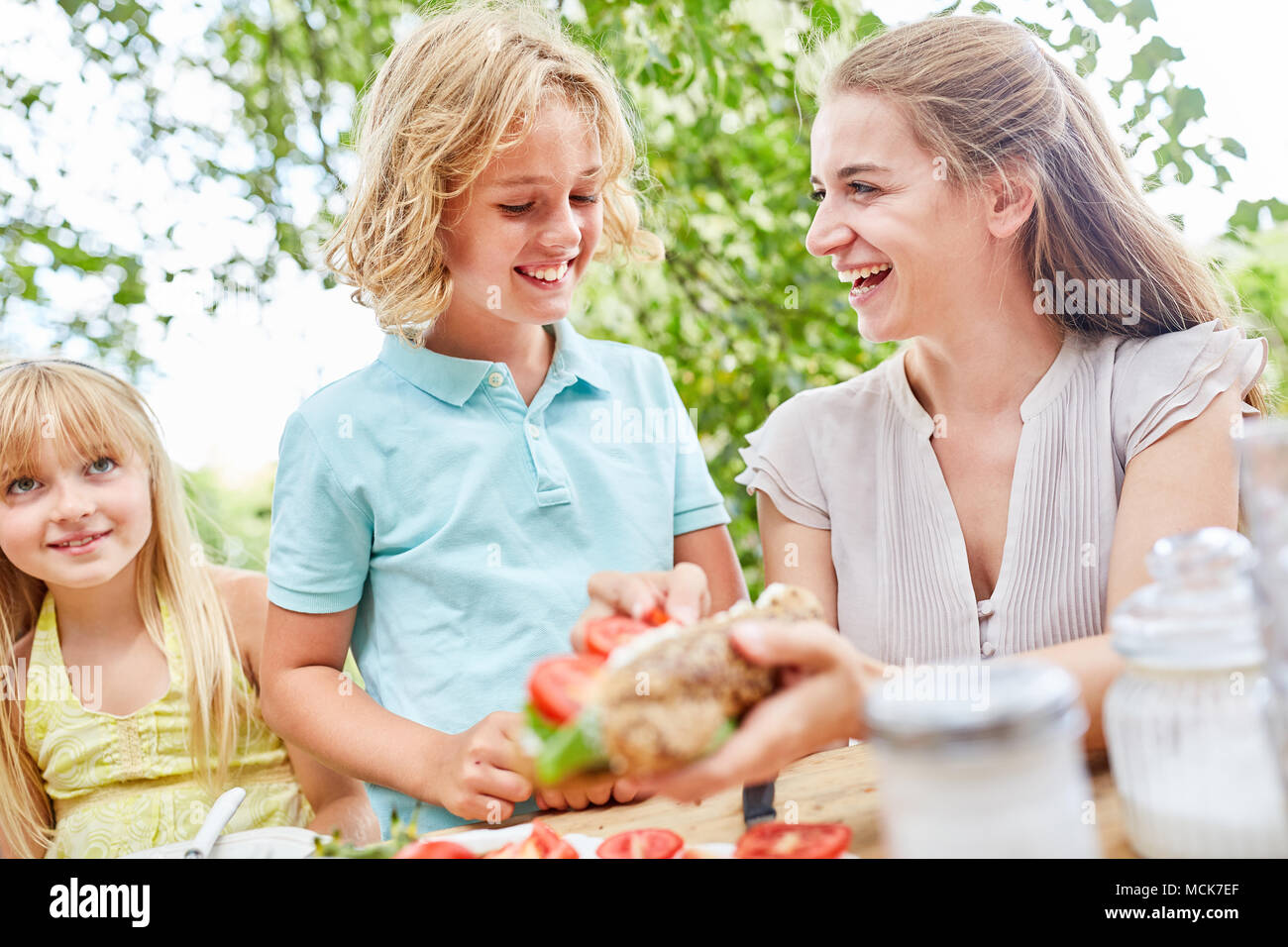 Mutter bereitet ein Baguette mit Tomaten für ihren Sohn zum Frühstück Stockfoto