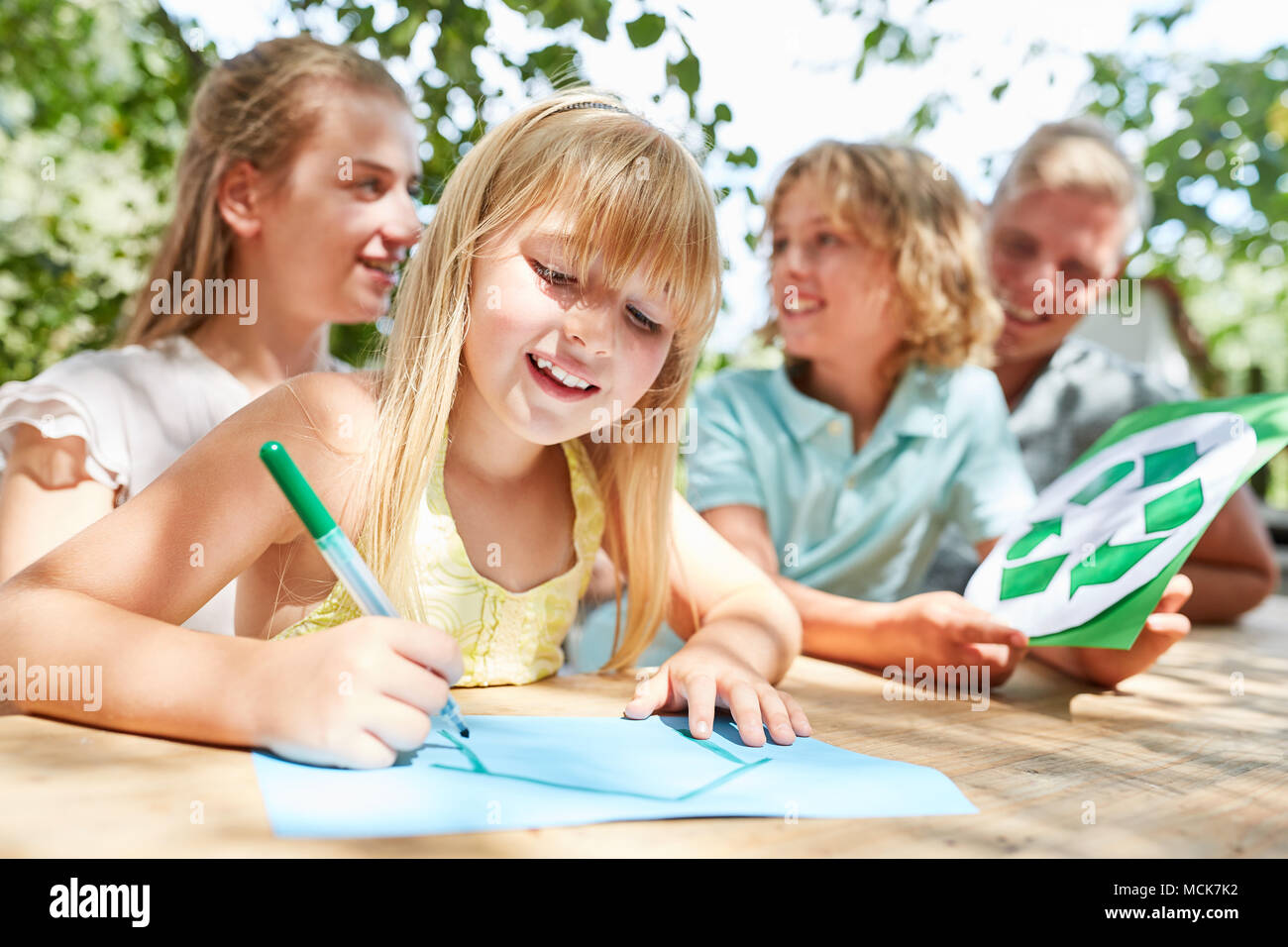 Blonde Mädchen ist Malen ein Haus und Bruder hält ein Papierkorb logo Stockfoto