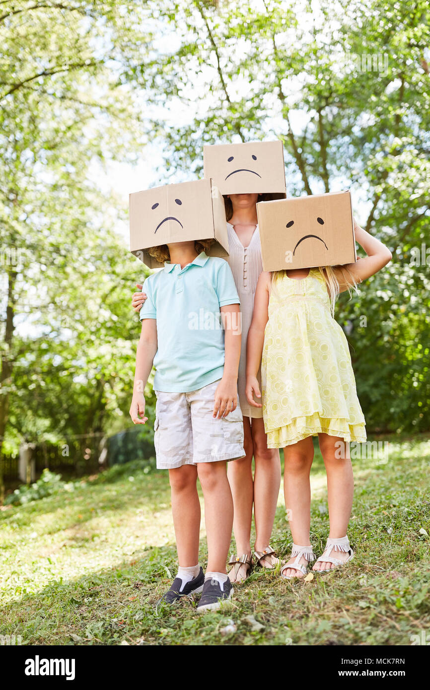 Familie mit Kindern steht im Garten in Kartons mit traurigen Gesichtern Stockfoto