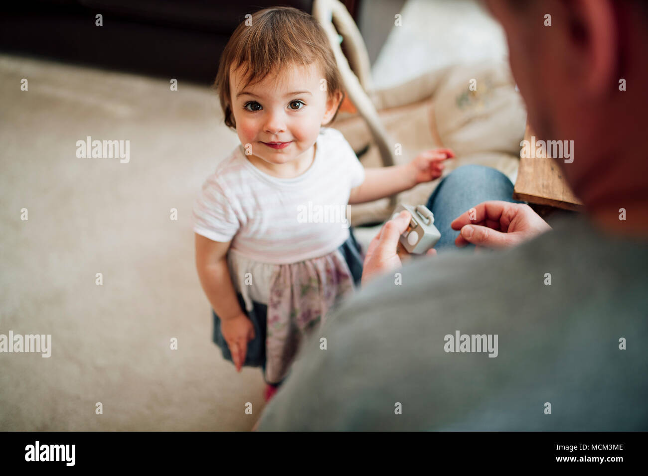 Kleines Mädchen hat aufgehört zu spielen mit ihrem Vater zu Hause in die Kamera schauen. Stockfoto
