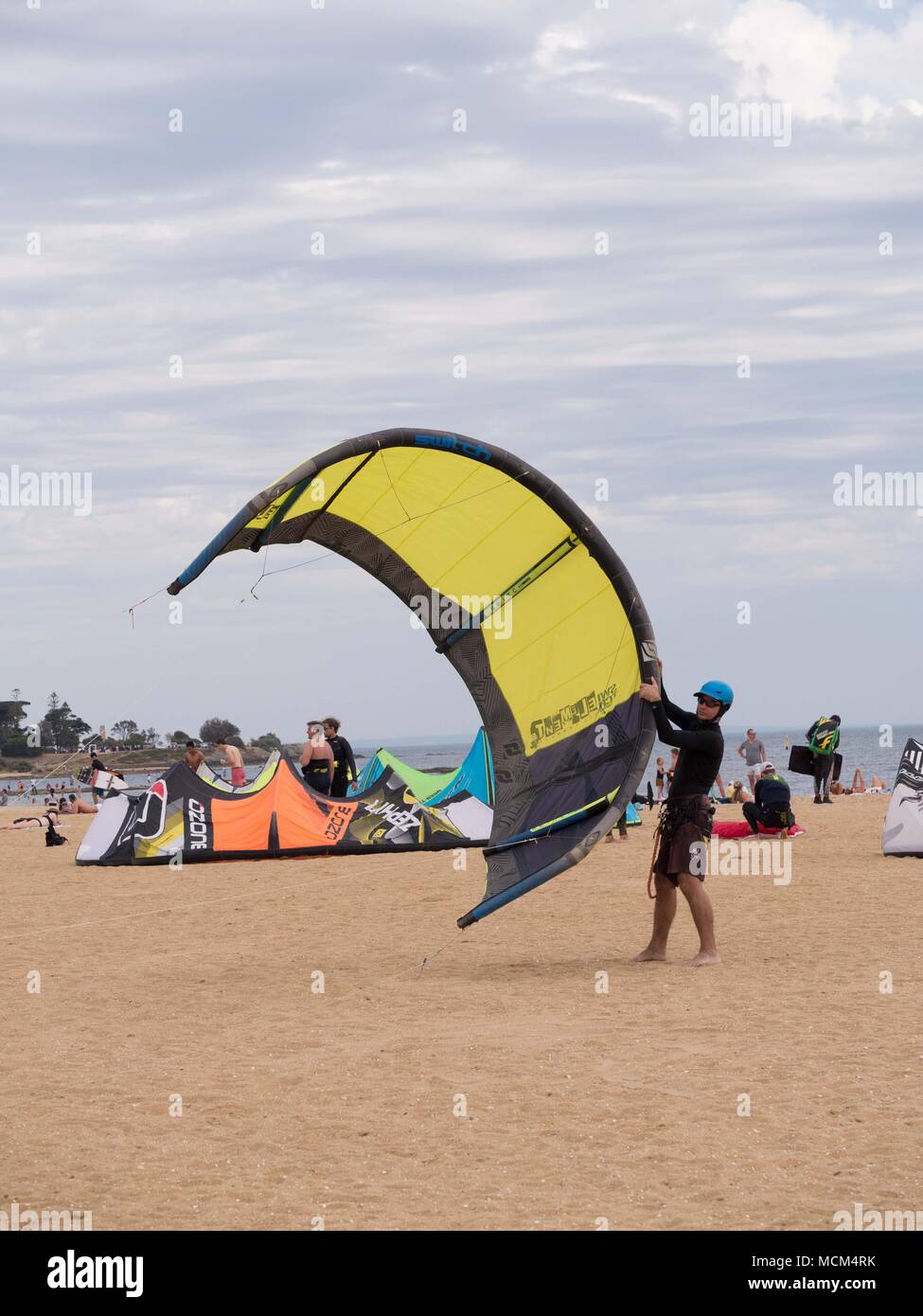 Die Menschen lernen, wie ein großes, gelbes kiteboard Kite an einem windigen Tag am Strand Start in Australien. Stockfoto