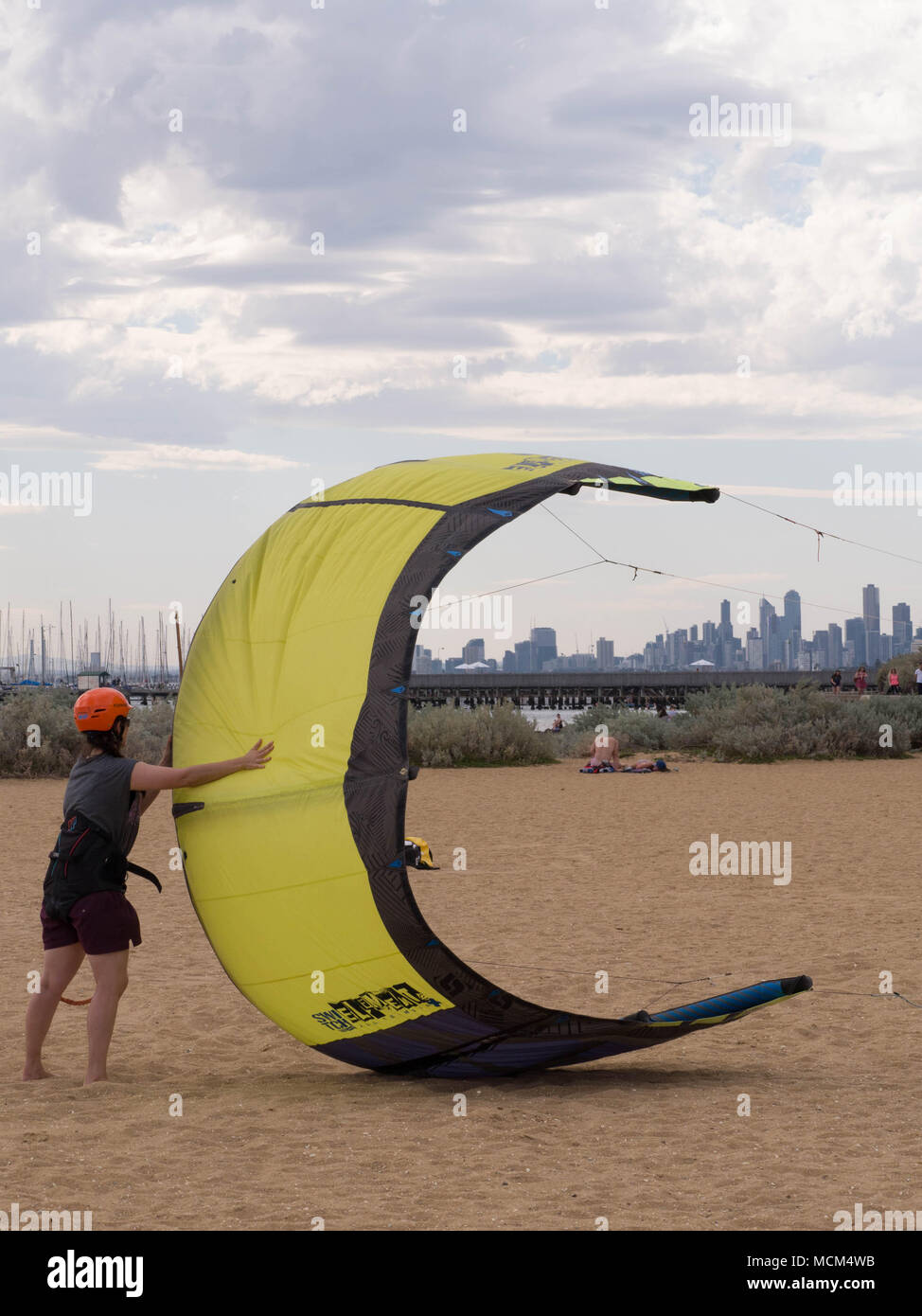 Die Menschen lernen, wie ein großes, gelbes kiteboard Kite an einem windigen Tag am Strand Start in Australien. Stockfoto