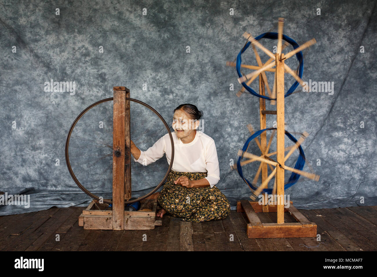 Ältere Frau sitzt auf Holzboden und Weben Seide auf Spinnräder, Shan Staat, Myanmar Stockfoto