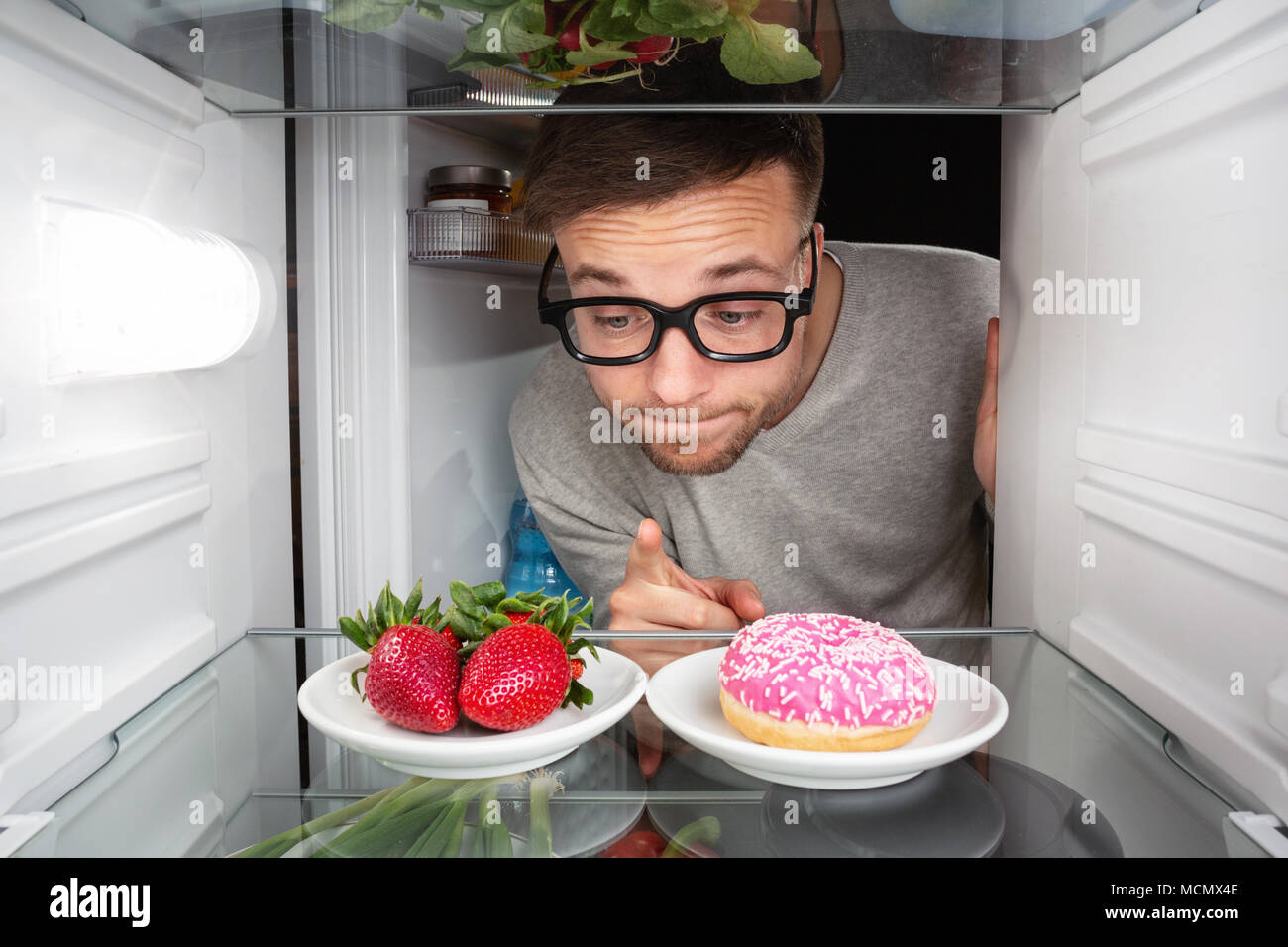 Mann die Wahl zwischen Obst und Süßigkeiten Stockfoto