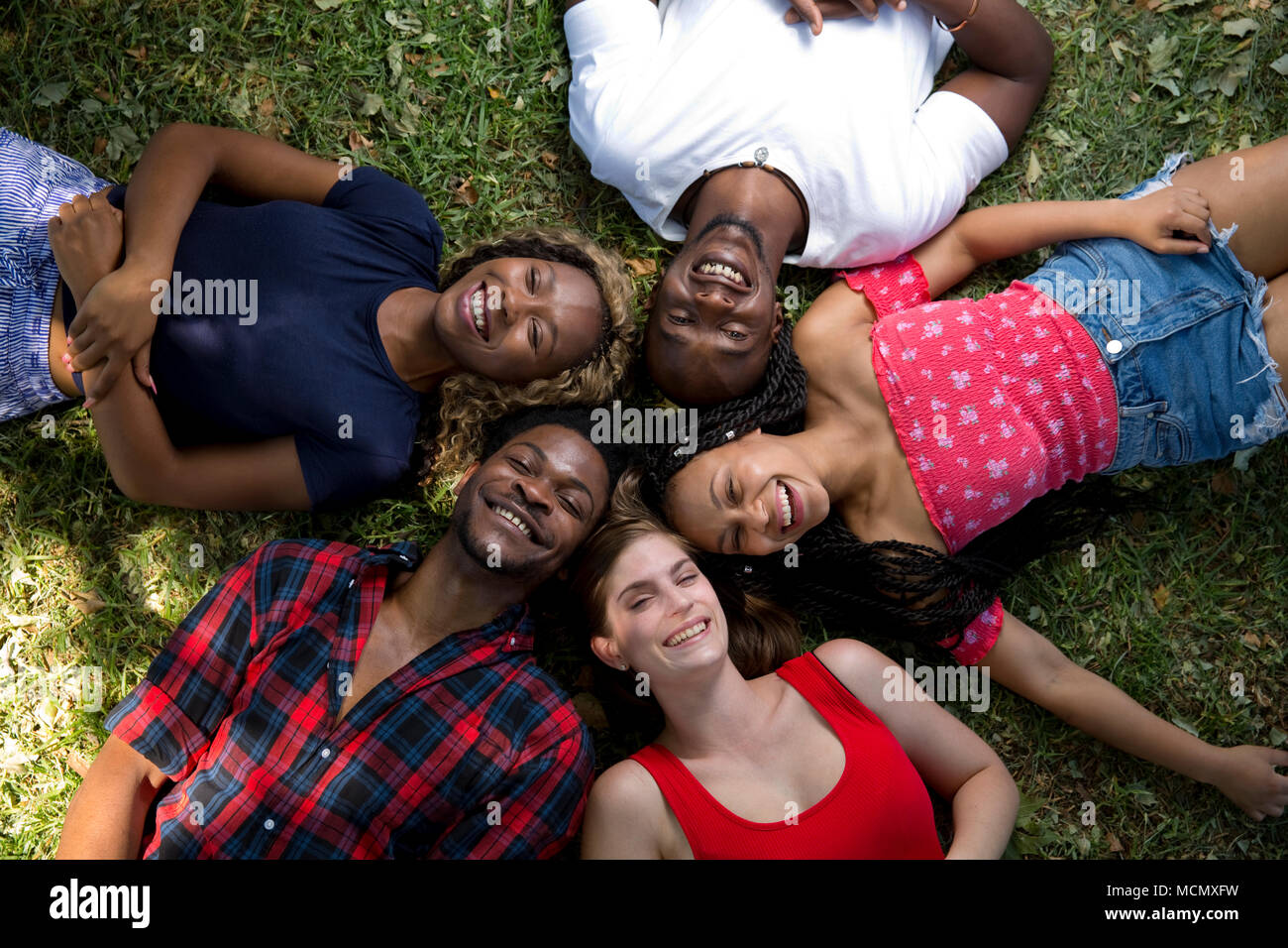 Eine Gruppe von Freunden, die auf dem Gras lachen Stockfoto