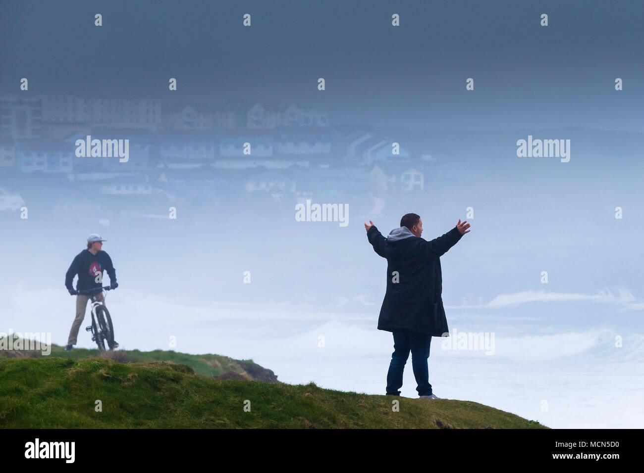 UK Wetter - ein Mann, der mit seinen ausgestreckten Armen an der Küste mit Blick auf das Meer in nebligen Wetter in Newquay Cornwall. Stockfoto