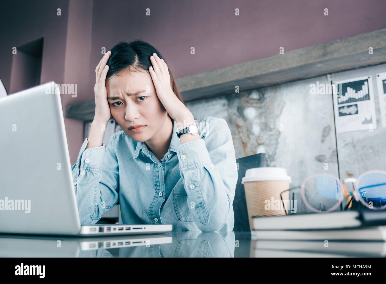 Asiatische Geschäftsfrau, die ihr Gesicht mit der Hand und Depression über die Arbeit in der Laptop auf dem Schreibtisch im Büro, Druck im Amt betonte Stockfoto