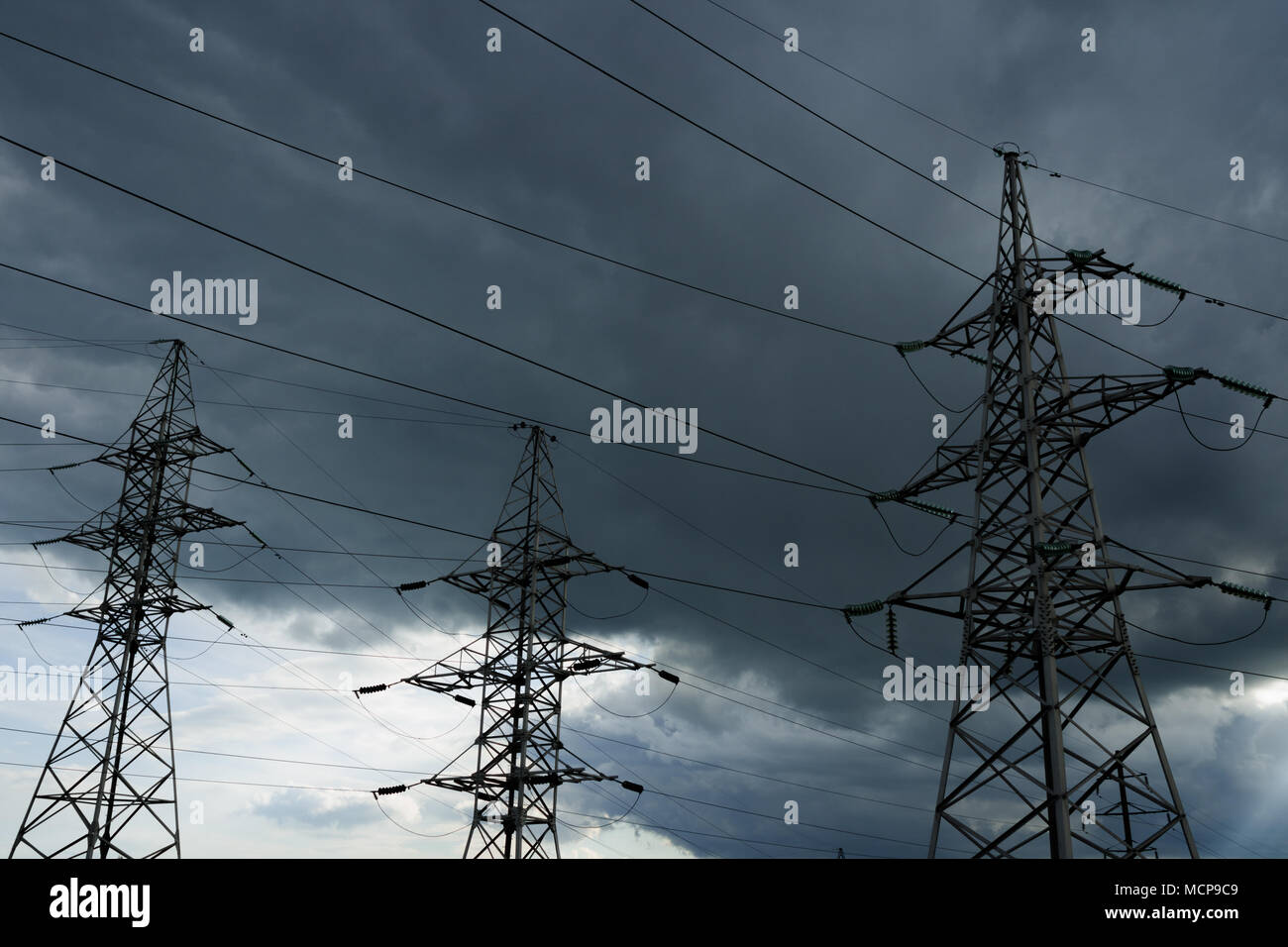 Hochspannung Strommasten gegen Gewitterwolke. Elektrische pole Leitungen und Drähte. Stockfoto