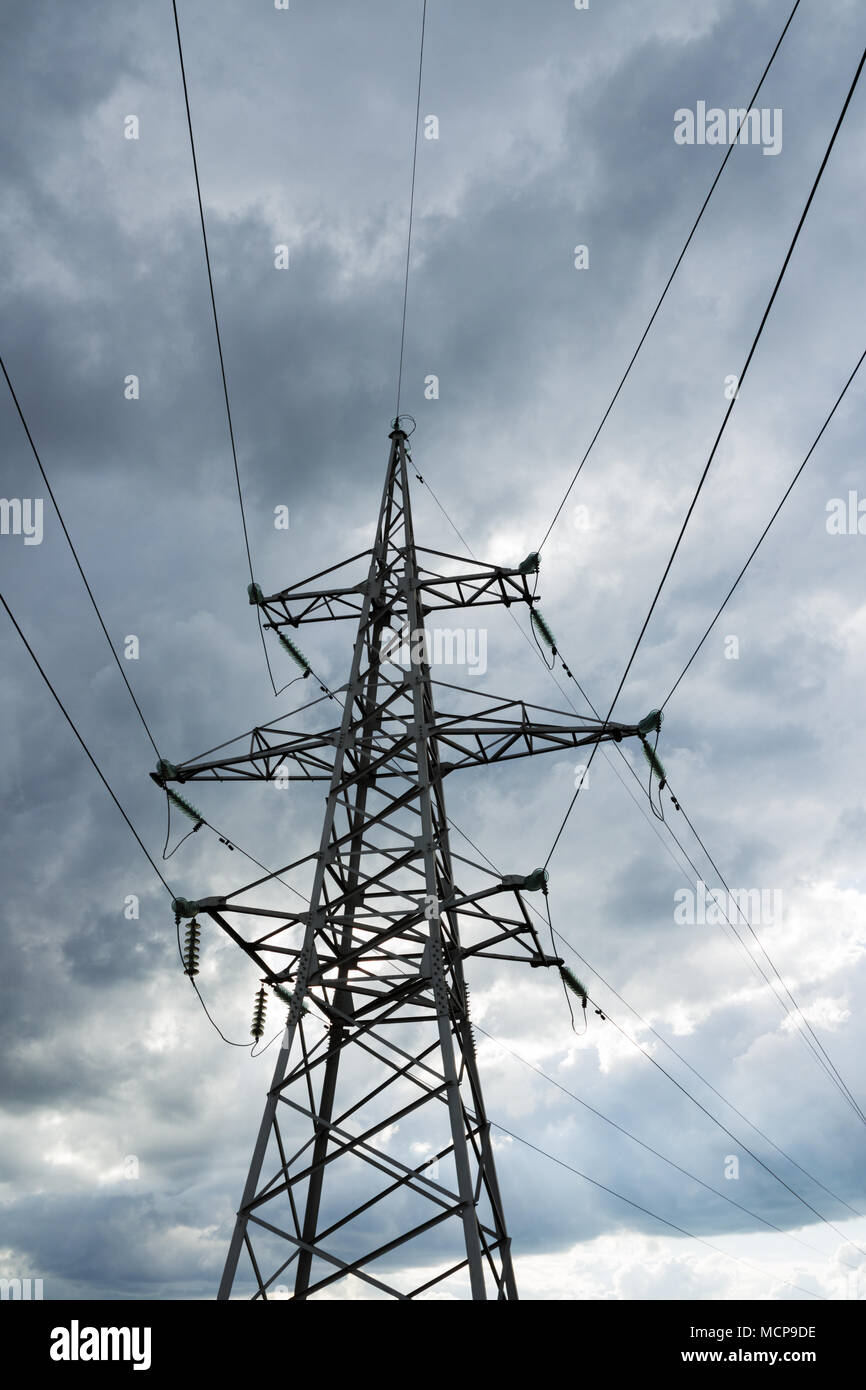 Hohe Spannung Strom pylon gegen Gewitterwolke. Elektrische pole Leitungen und Drähte. Stockfoto
