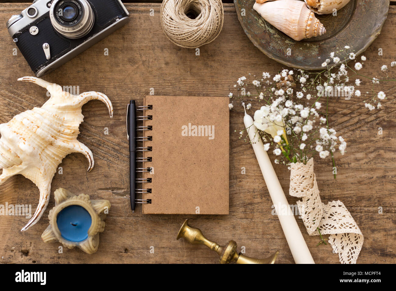 Rusitc Hochzeit Konzept. Zusammensetzung mit notepad durch kleine gypsophila Bouquet, Seashell, Kerzen, Kerzenhalter und Film Kamera umgeben zentriert. Stockfoto