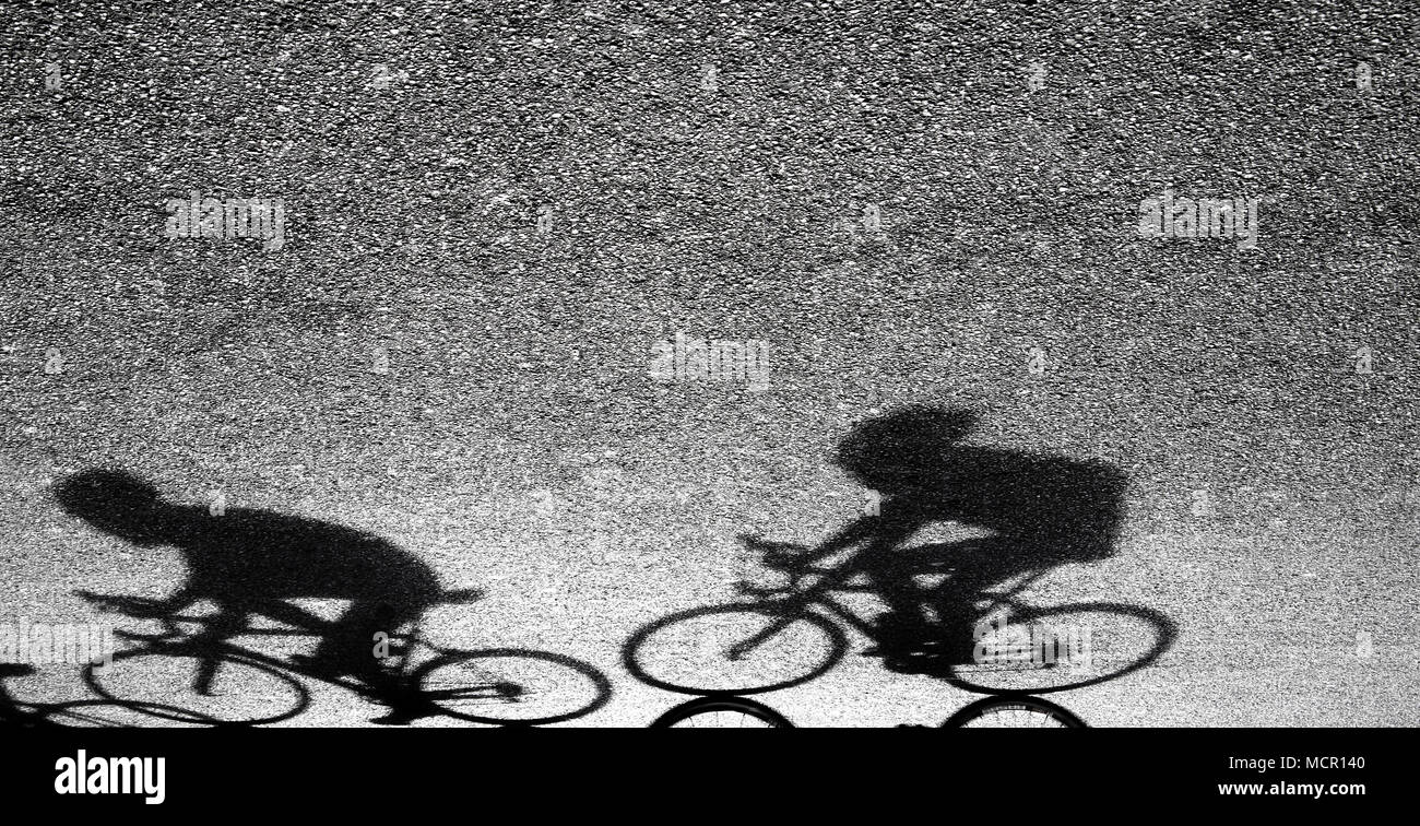 Unscharfe Silhouette und Schatten der zwei professionelle Radfahrer in Schwarz und Weiß auf Asphalt Stockfoto