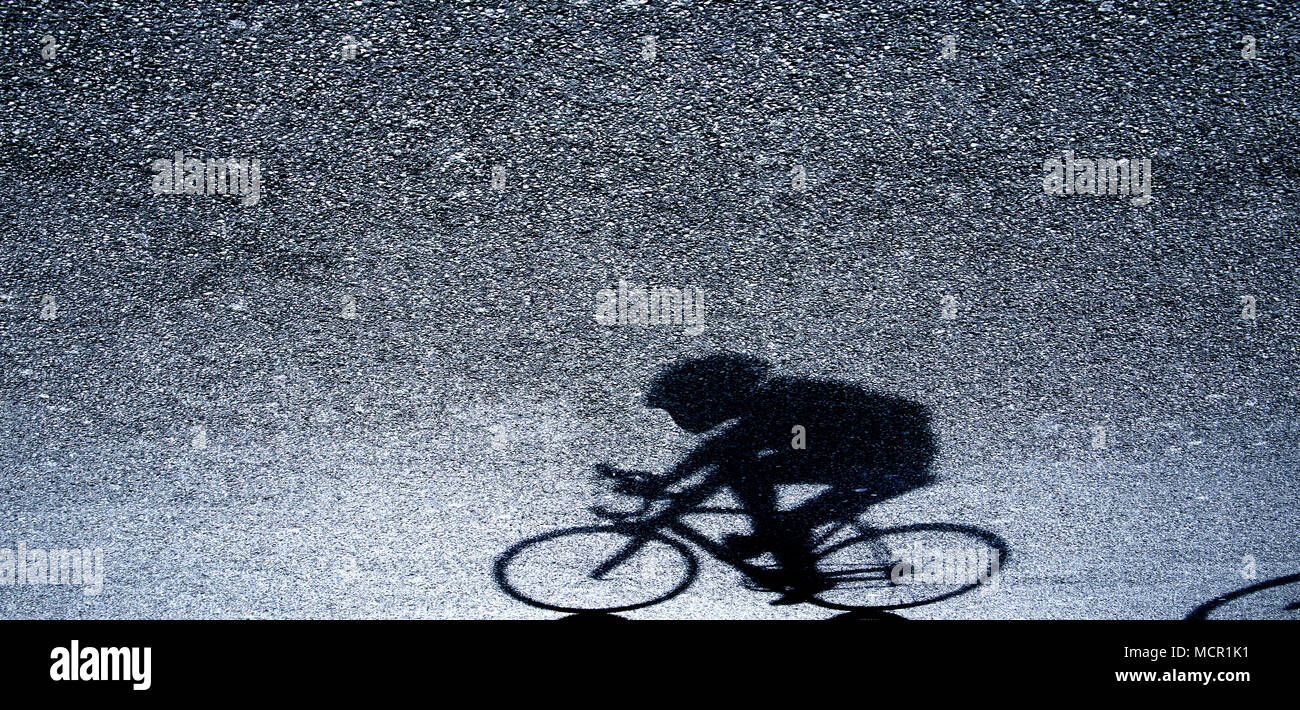 Unscharfe Silhouette und Schatten eines Radprofi in Schwarz und Weiß auf Asphalt in der Nacht Stockfoto