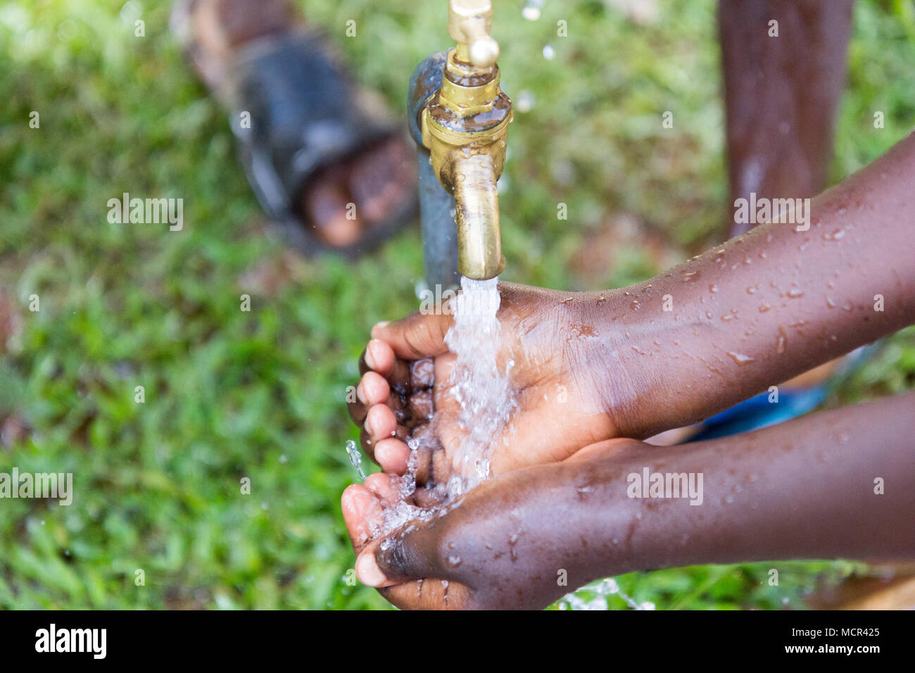 Ugandische Kinder waschen ihre Hände an einer im Leitungswasser Stockfoto