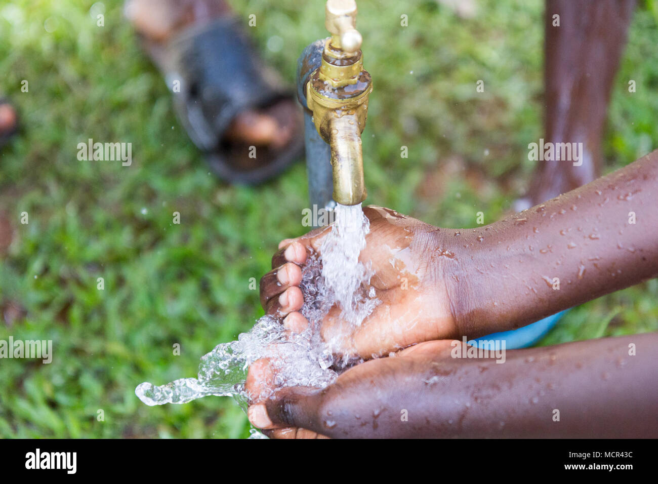 Ugandische Kinder waschen ihre Hände an einer im Leitungswasser Stockfoto