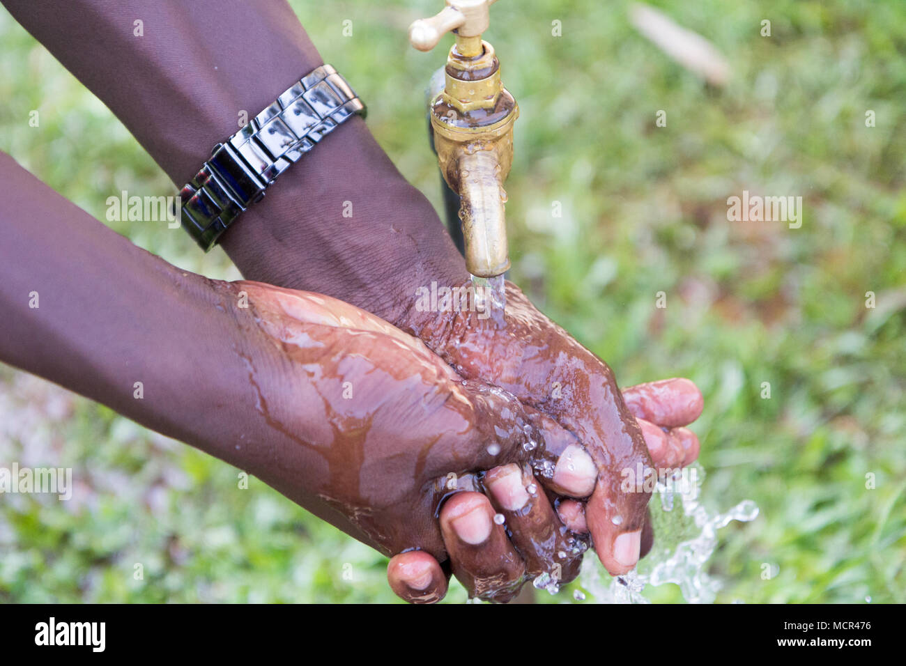 Ugandische Kinder waschen ihre Hände an einer im Leitungswasser Stockfoto