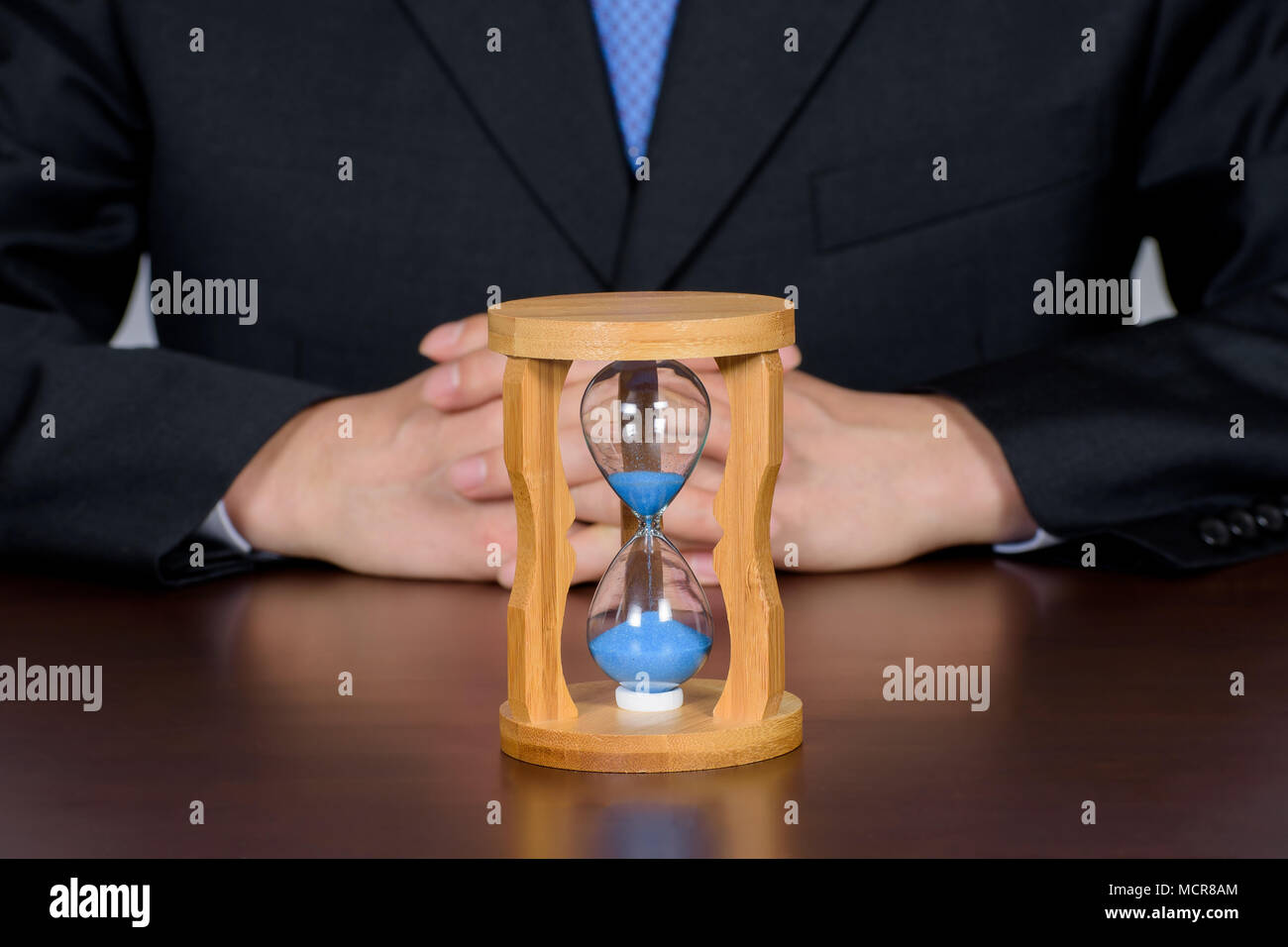 Geschäftsmann mit den Händen hinter dem Rücken der Sanduhr Stockfoto