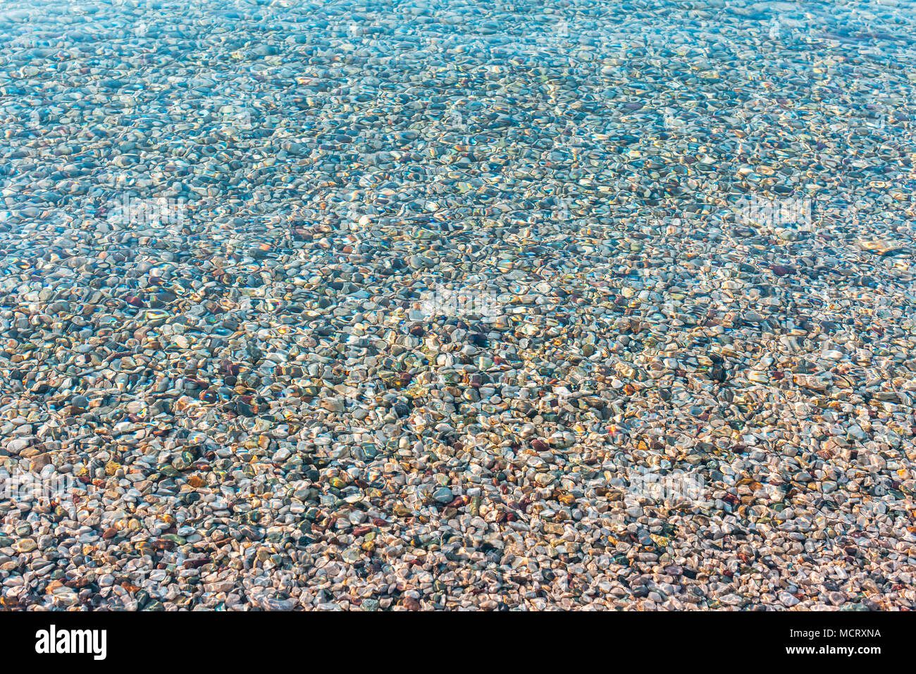 Hintergrund der farbenfrohen Meer Steine unter Wasser verschwommen. Irisierende das Sonnenlicht auf die Steine. Transparente klare Wasser des Meeres. Farben Foto Stockfoto