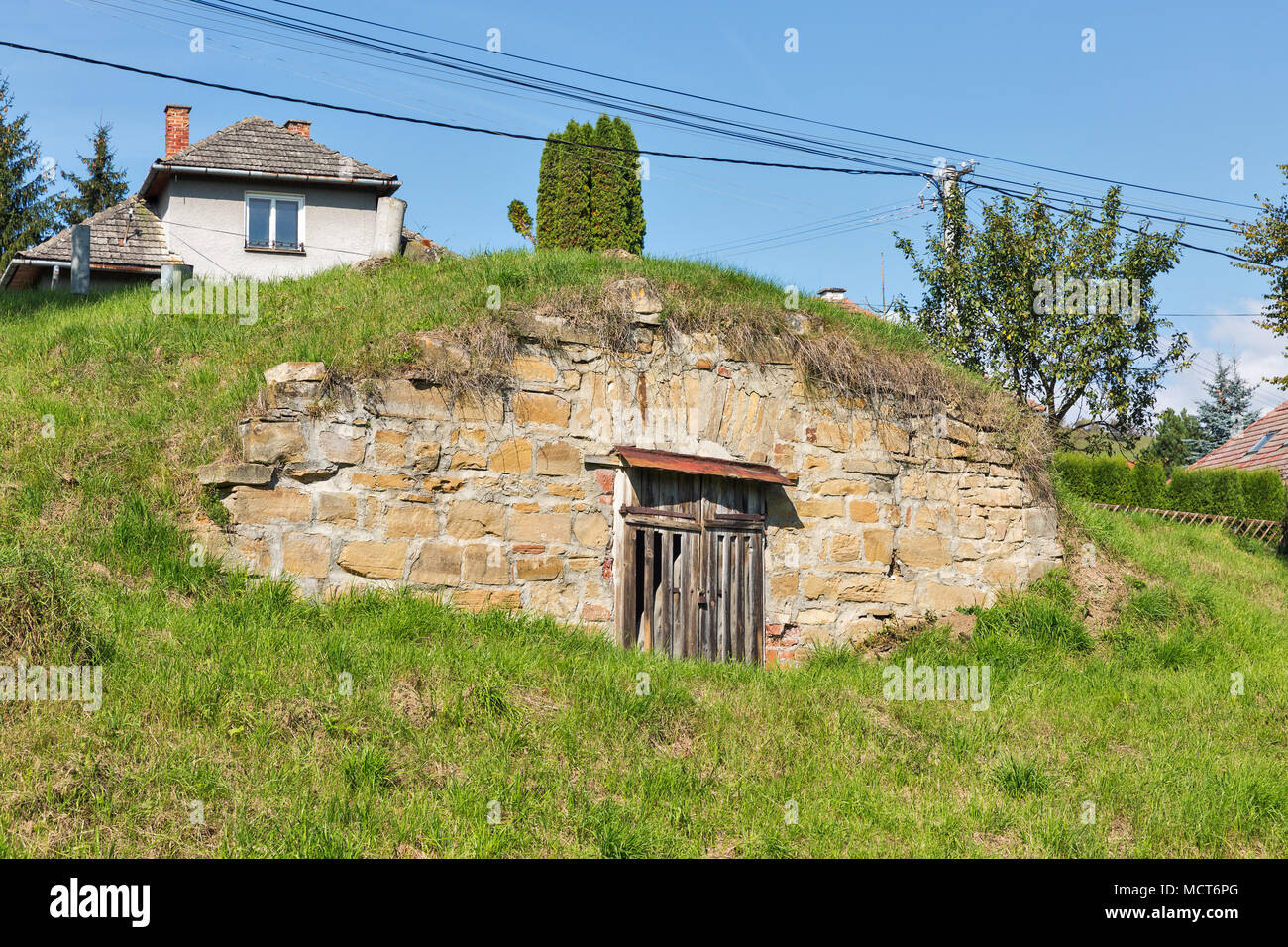 Ländliche Straße mit typischen Cottages in einer Zeile, blau klaren Himmel und Hügel im Hintergrund Stockfoto