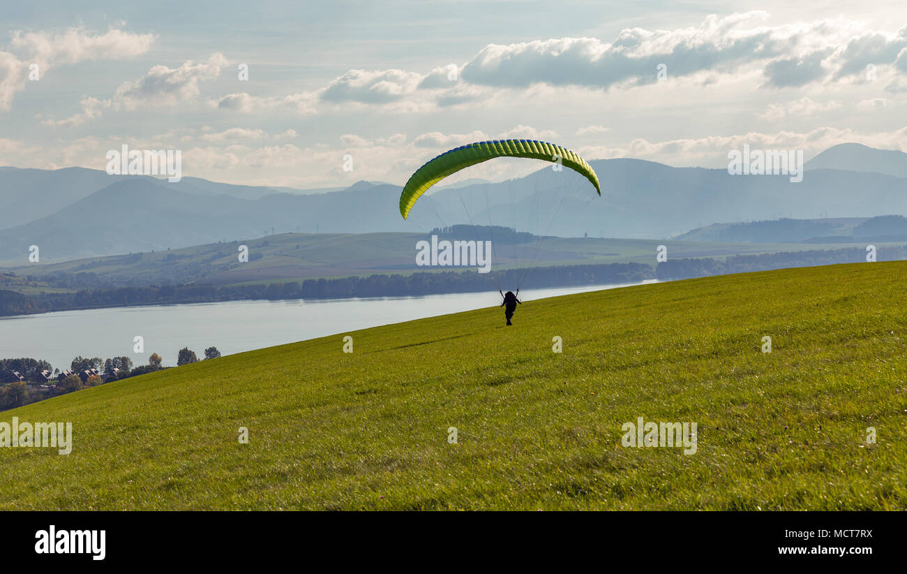 Gleitschirm startet Flug aus der Hügel über Liptovska Mara Lake in der Nähe von Liptovsky Trnovec ist Dorf in der Slowakei. Extreme sportliche Aktivität. Stockfoto
