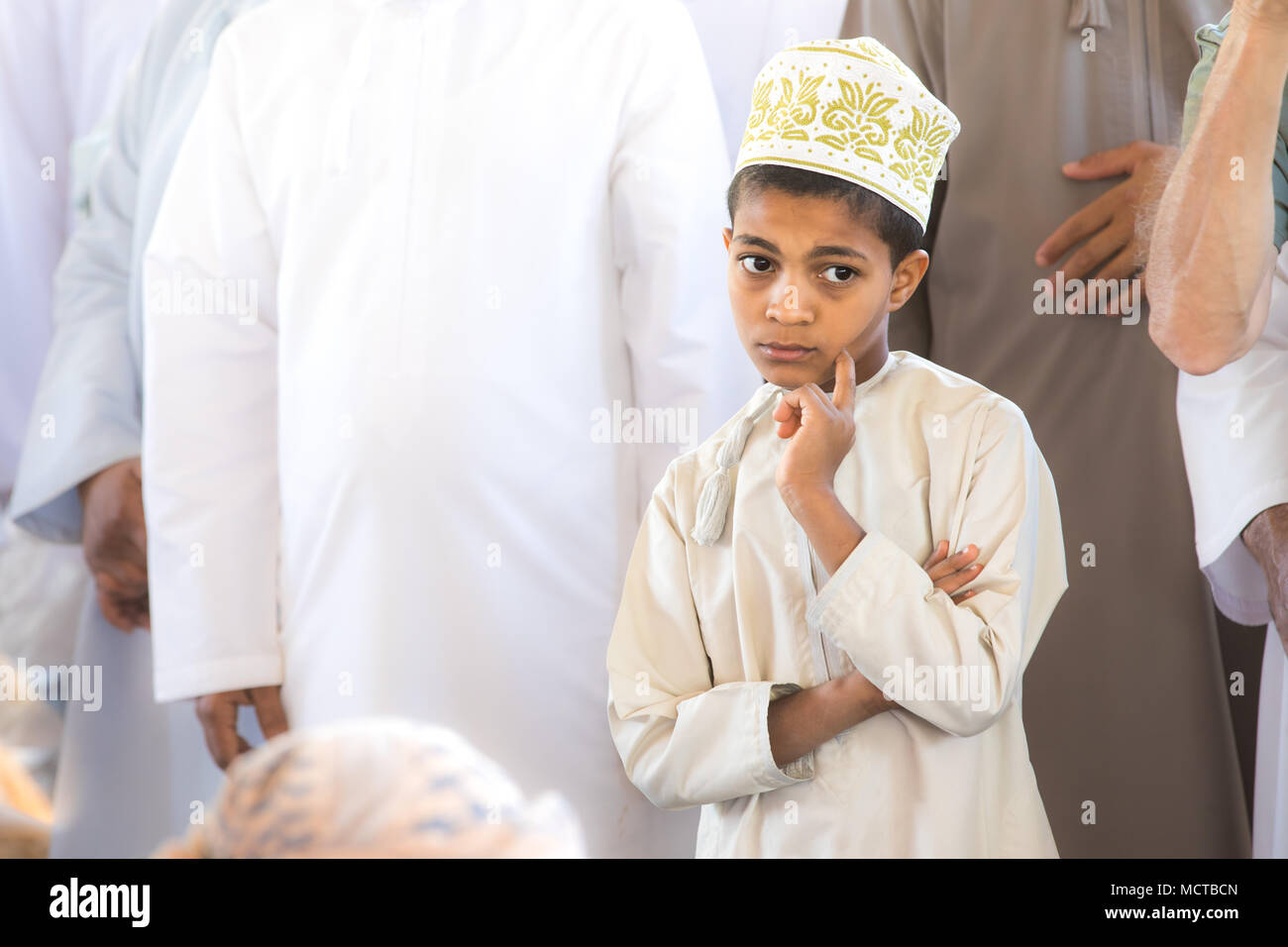 Nizwa, Oman - Mar 23, 2018: Junge hübsche Omanische Junge in einer durchdachten in traditionellem Weiß lokale Kleidung darstellen. Stockfoto