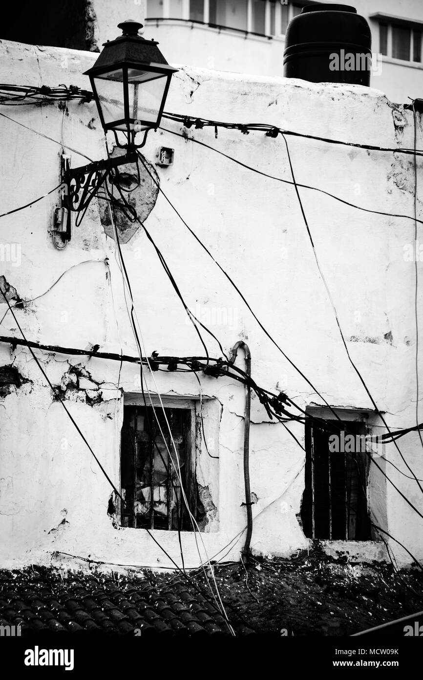 Altmodische schwarz-weiß Bild von einer Hausfassade mit Hochspannungsleitungen, elektrische Installationen und einer Laterne in Casablanca, Marokko Stockfoto