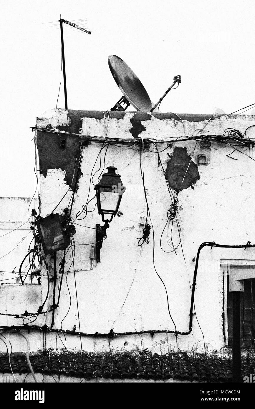 Altmodisches Bild einer Hausfassade mit Hochspannungsleitungen, elektrische Installationen und eine Satellitenschüssel in Casablanca, Marokko Stockfoto