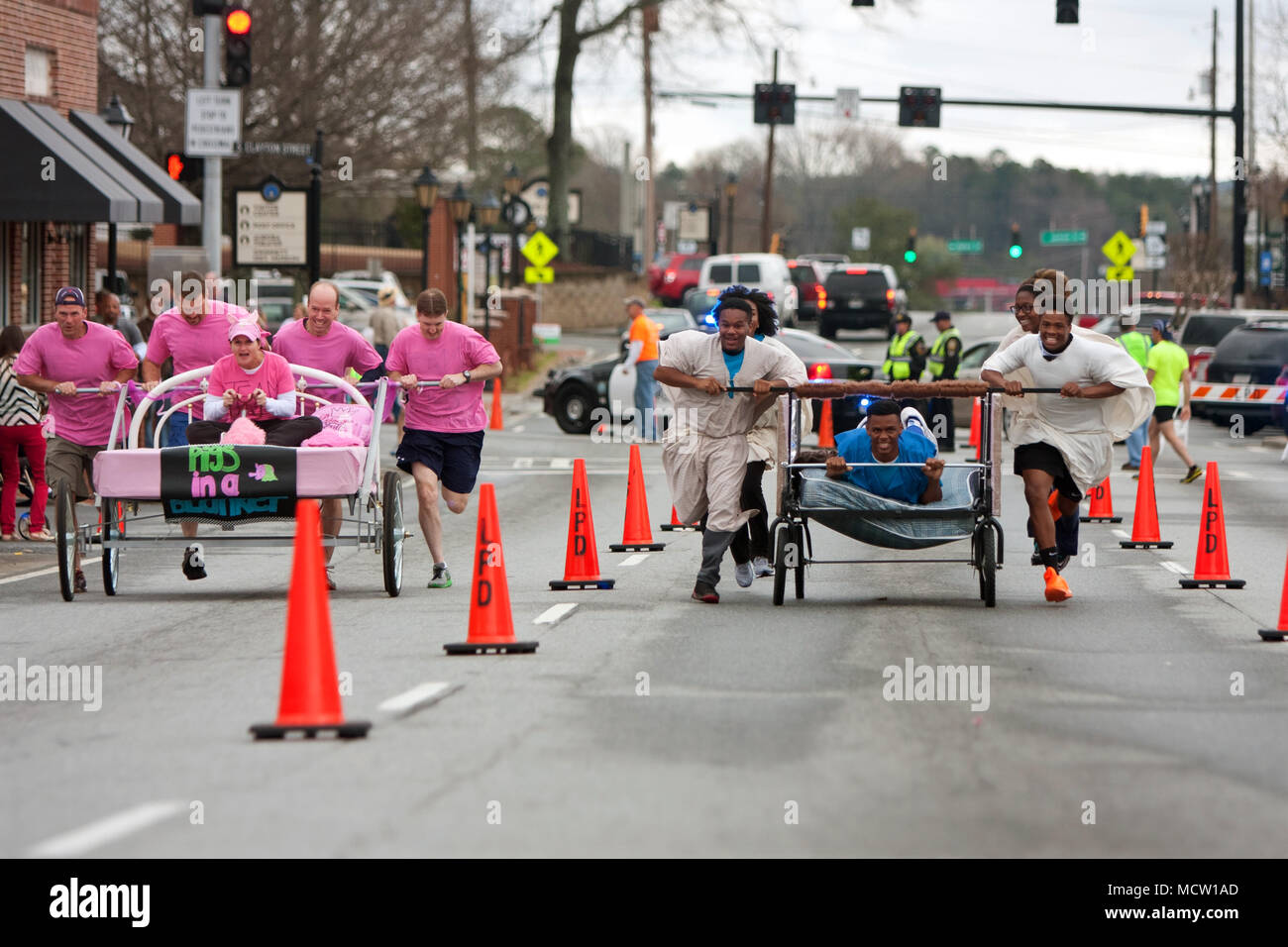 Zwei Mannschaften drücken Sie dumme Suchen Betten durch die Innenstadt von Straßen in der jährlichen Lawrenceville Bett Rennen, am 29. März 2014 in Lawrenceville, GA. Stockfoto