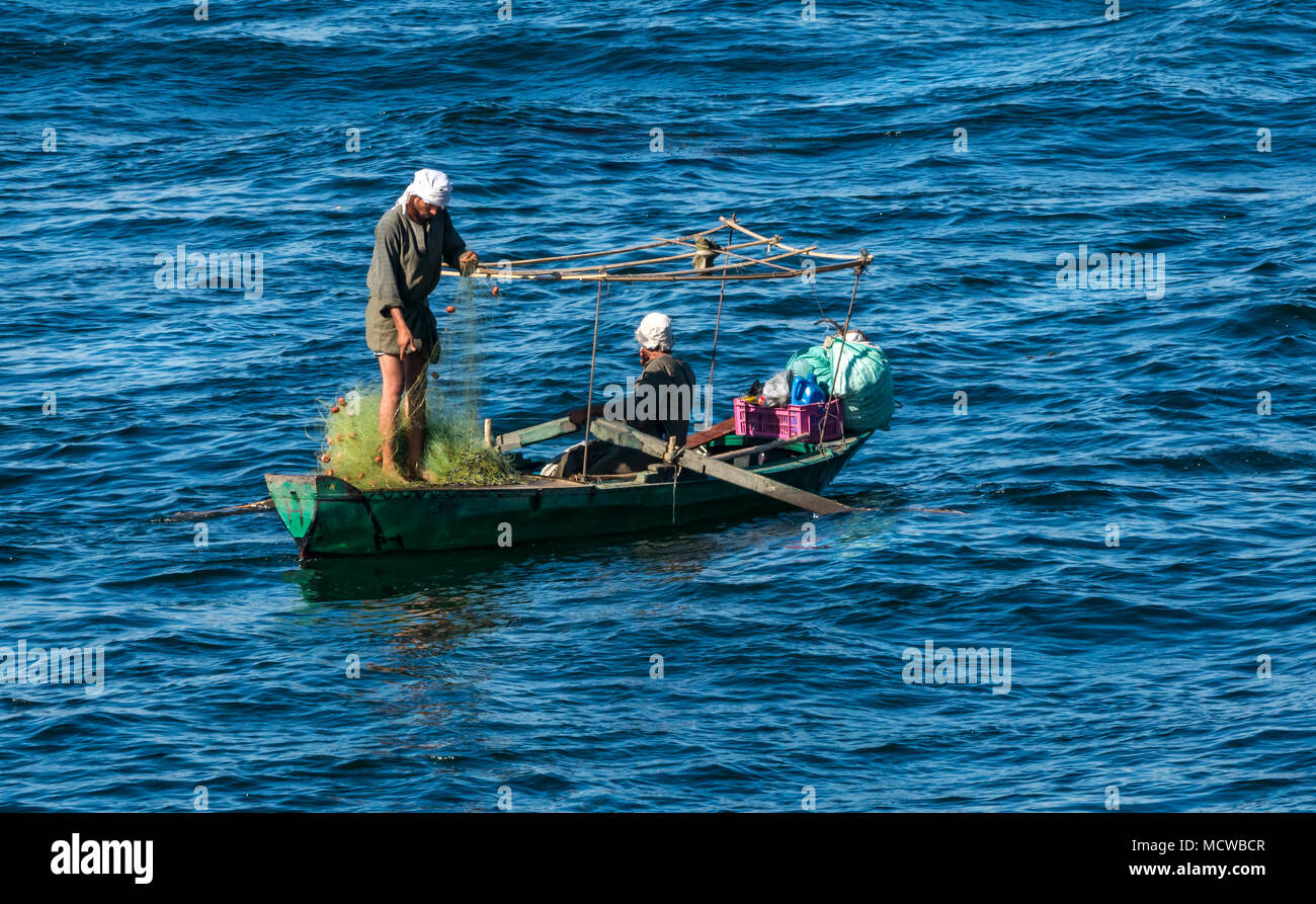 Zwei ägyptische einheimische Männer in traditioneller Kleidung und Turbane in kleinen Ruderboot mit Fischernetze, Morgenlicht, Nil, Ägypten, Afrika Stockfoto