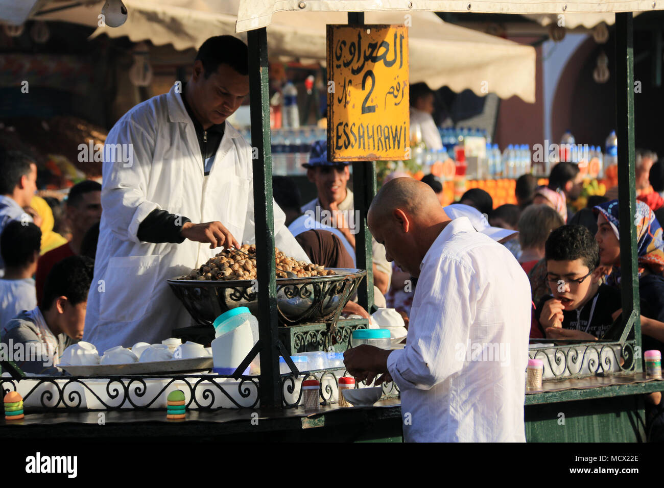 Marokkanische Koch Kochen Schnecken hinter der Theke seiner Nahrung  Warenkorb stall während ein Mann die exotische Delikatesse genießt, Jemaa  el-Fnaa, Marrakesch, Marokko Stockfotografie - Alamy