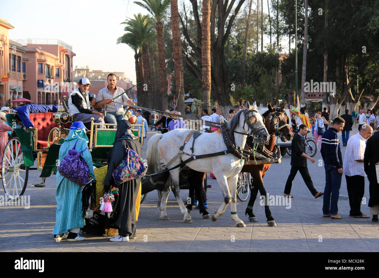 Zwei arabische Frauen in traditioneller Kleidung mit Kutscher von einem Fiaker vorbei an der berühmten Place Jemaa el-Fnaa Platz in Marrakesch, Marokko Stockfoto