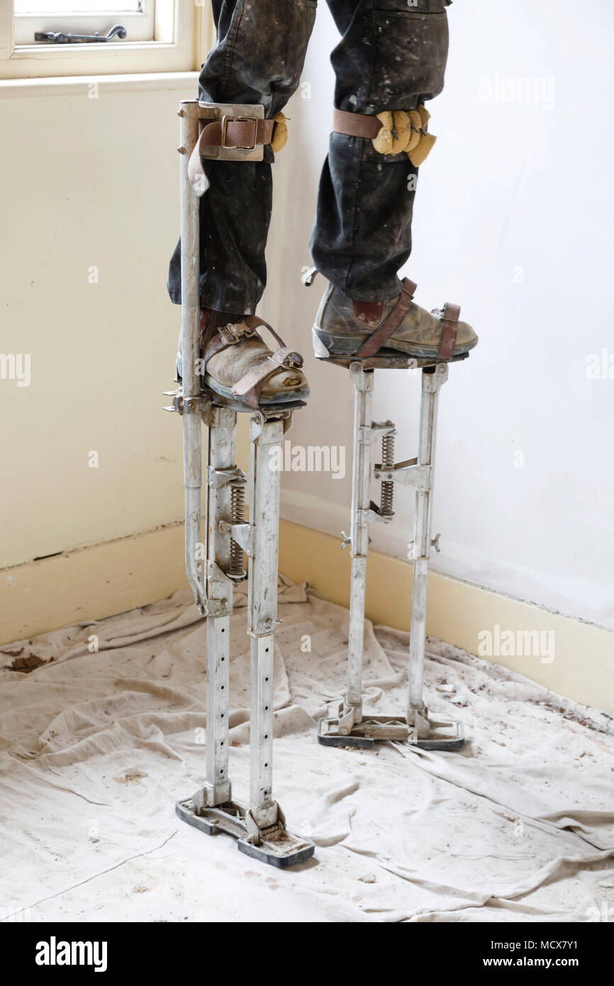 Gipser auf Stelzen verputzen Eine hohe Decke Stockfoto