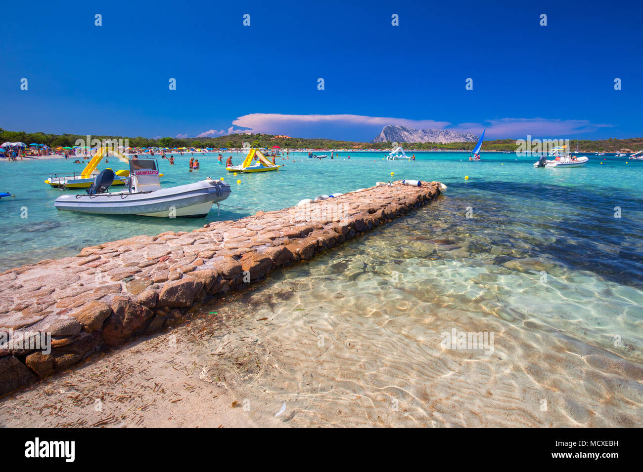 CALA BRANDINCHI, Sardinien - August 2017 - Cala Brandinchi Strand mit Isola Travolara im Hintergrund, rote Steine und azurblauen Wasser, Sardinien, Es Stockfoto