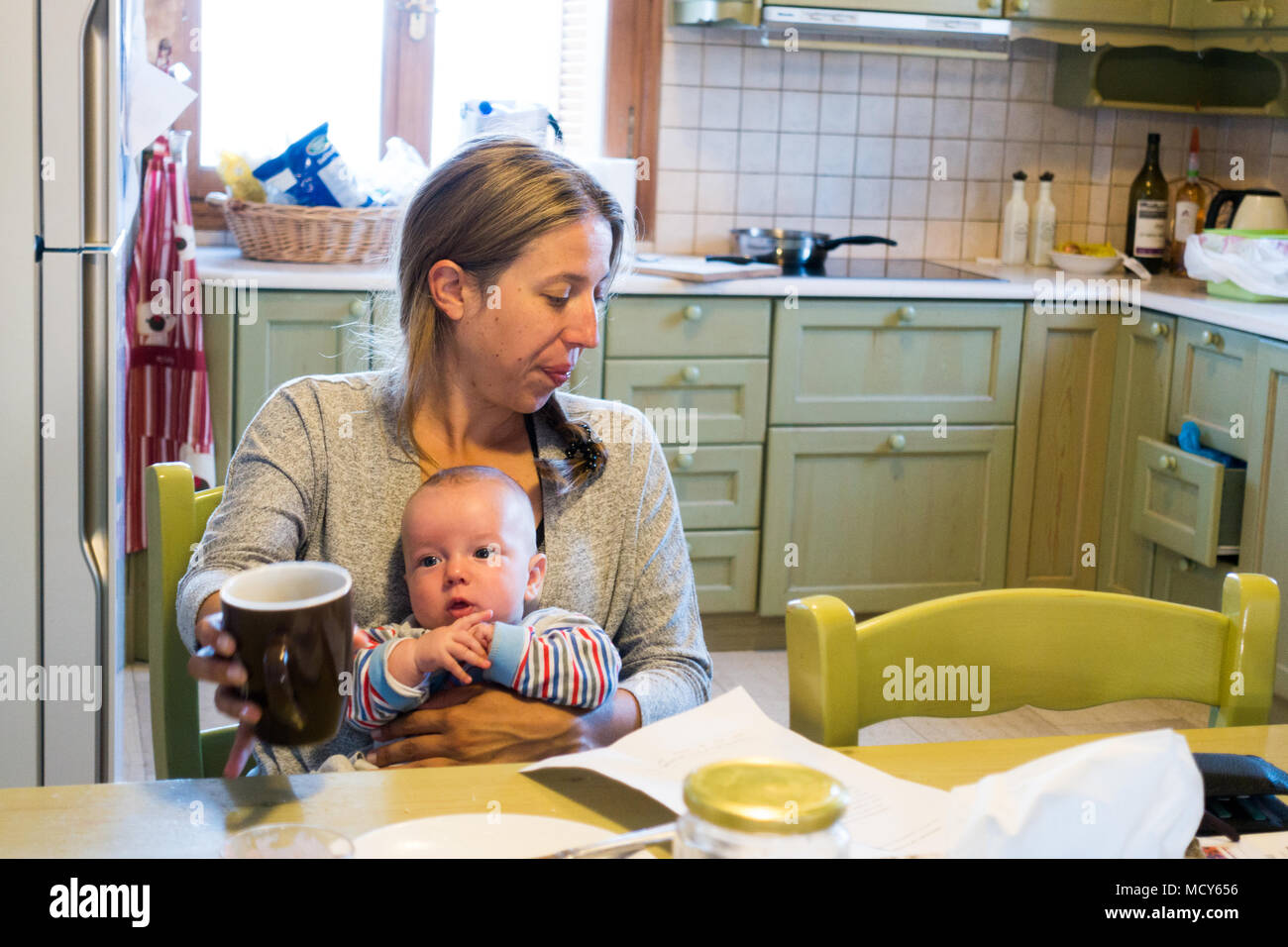 Mutter mit Baby am Esstisch in der Küche zu Hause sitzen Stockfoto
