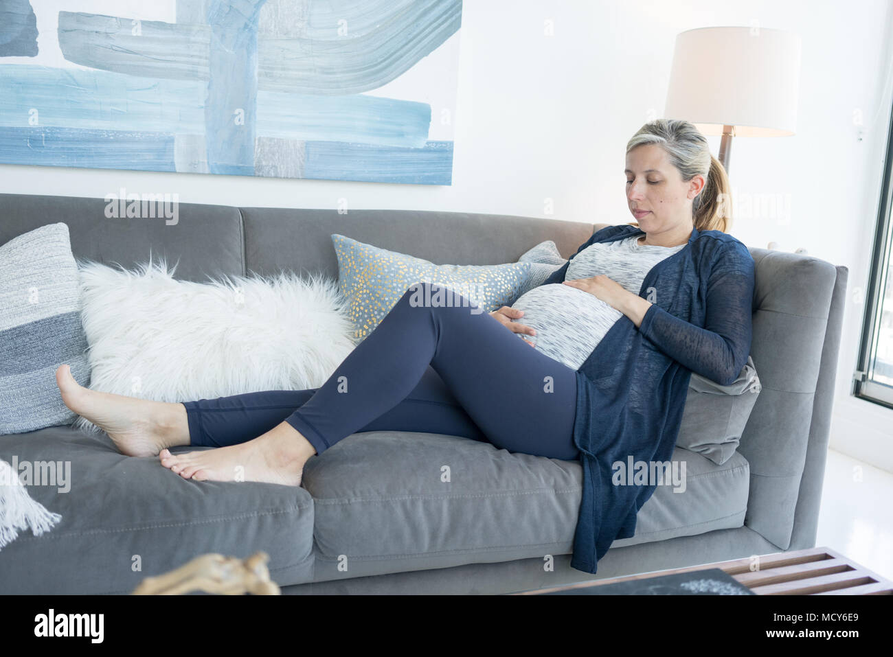 Liegende Frau auf Sofa und berühren ihre schwangeren Bauch Stockfoto