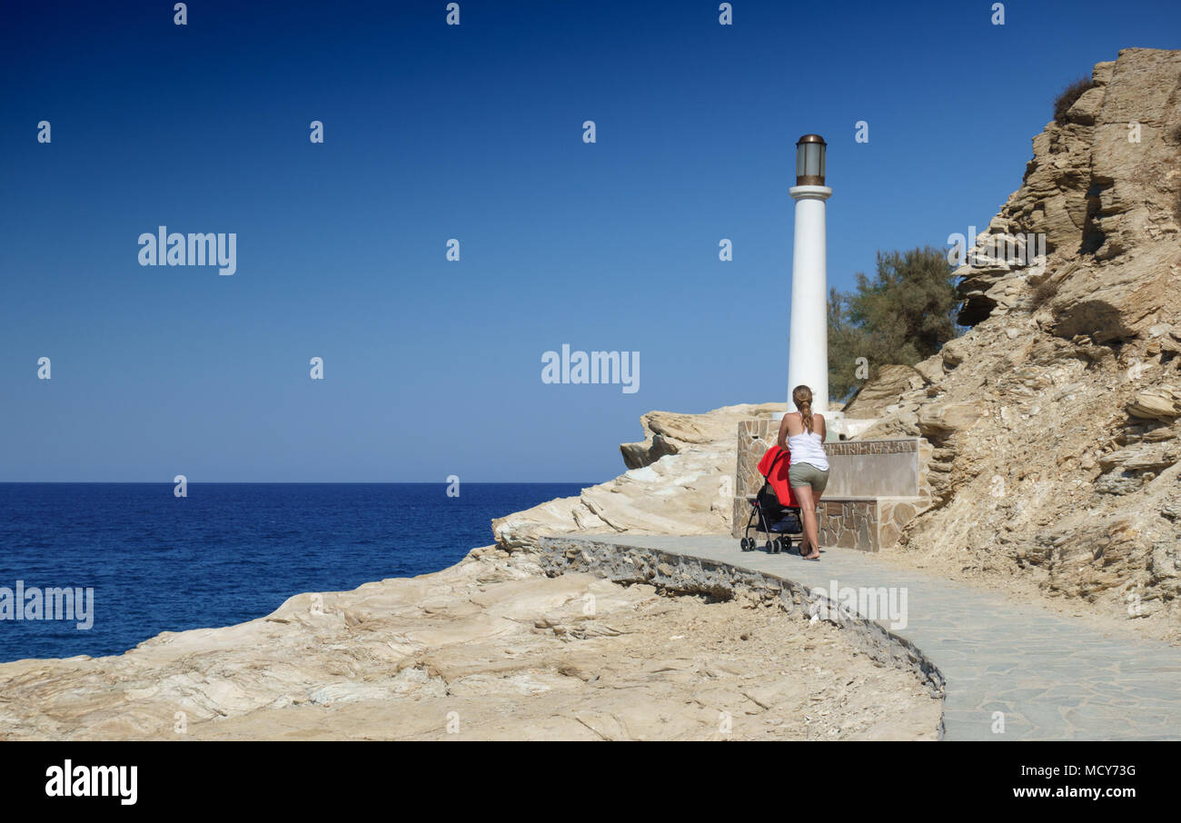 Malerischer Blick auf Meer mit Frau schieben Kinderwagen auf der Küstenstraße, Heraklion, Griechenland Stockfoto
