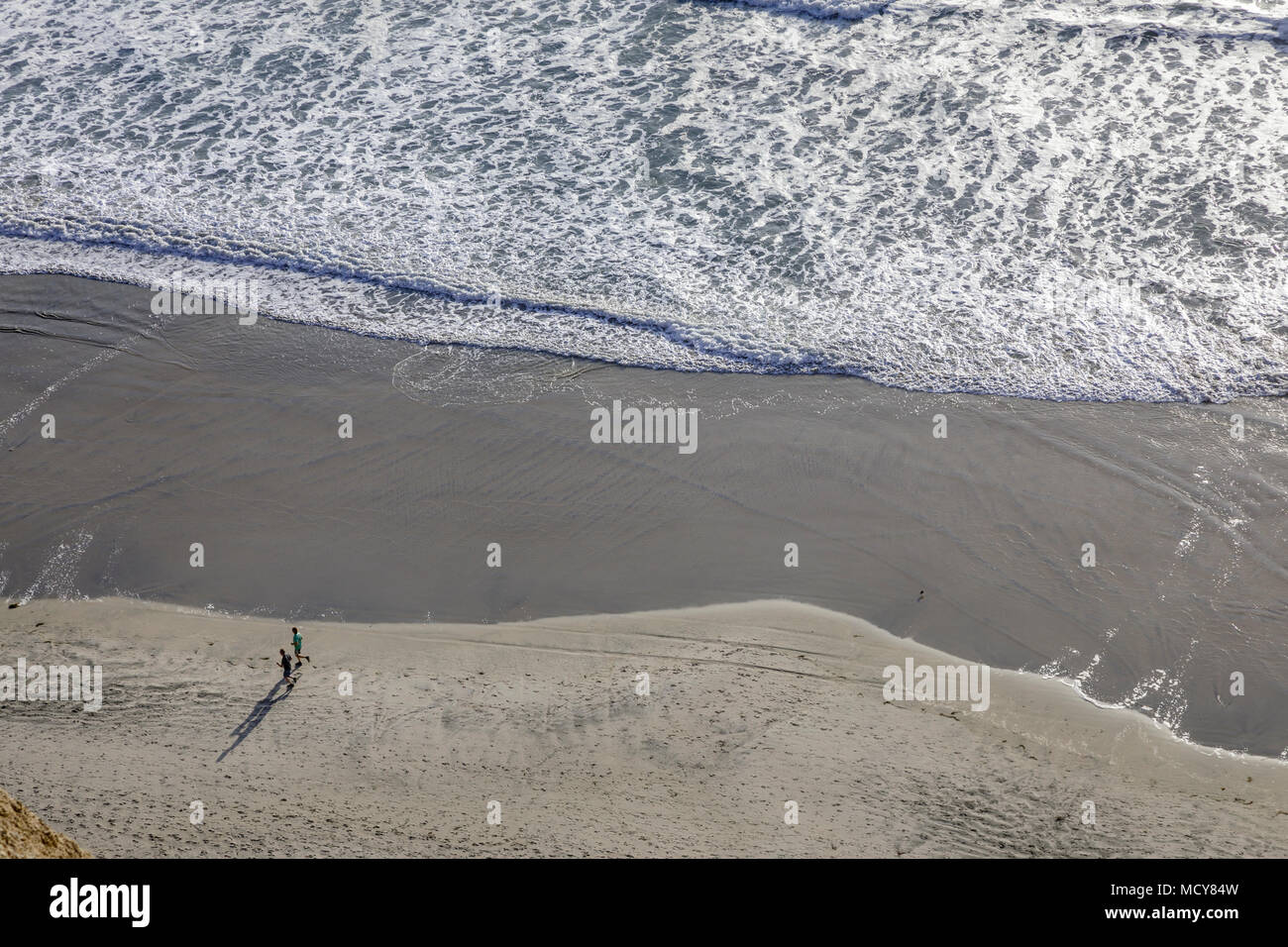 Ein hoher Overhead Ansicht einer Person zu Fuß am Strand entlang mit Wellen in Rollen. Stockfoto