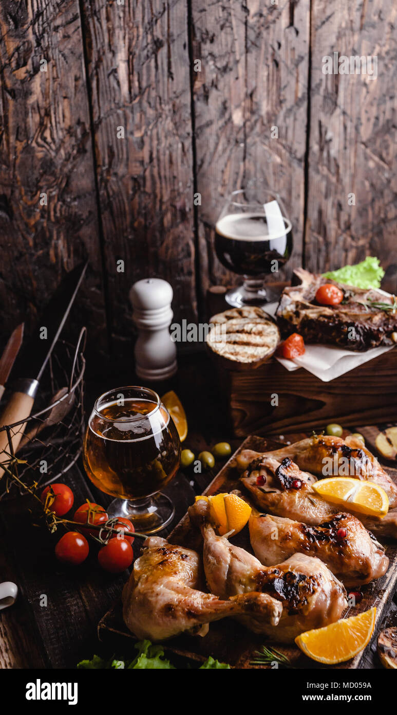 Lecker gegrilltes Fleisch mit Gemüse und Bier auf Holz- Hintergrund Stockfoto