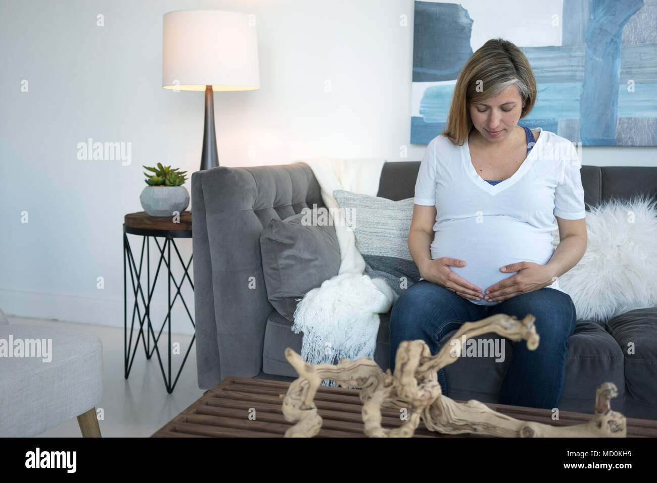 Frau sitzt auf einem Sofa und berühren ihre schwangeren Bauch Stockfoto