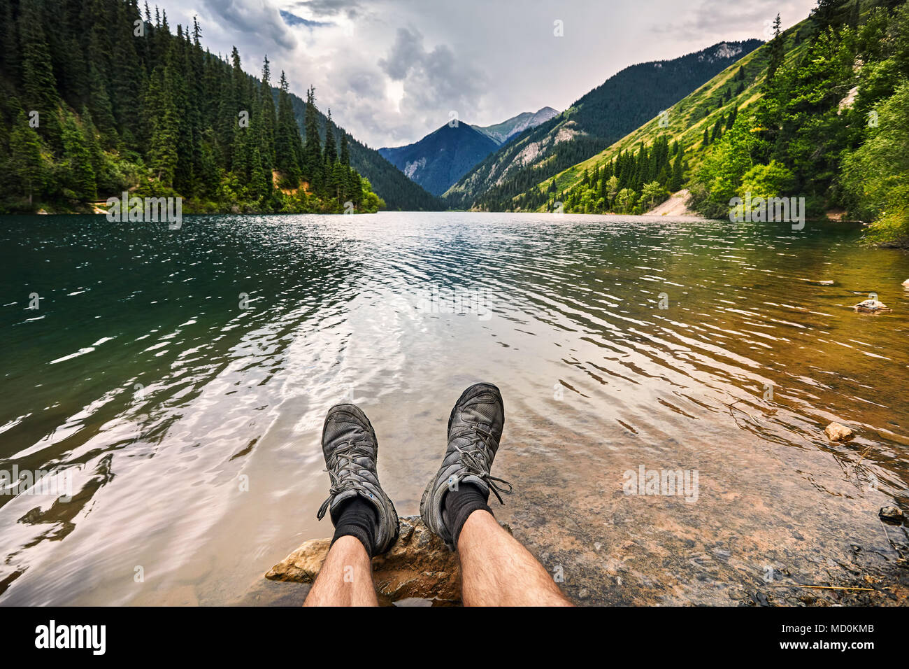Reisende Bein mit Schuhe am schönen Blick auf hoher See Kolsai im Sommer in Kasachstan und Zentralasien Stockfoto