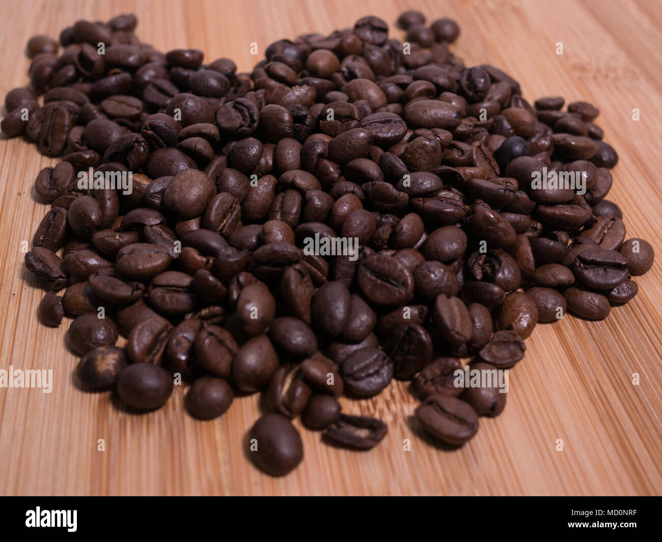 Frisch geröstete Kaffeebohnen closeup auf natürliche Holzoberfläche Ansicht von oben. Stockfoto